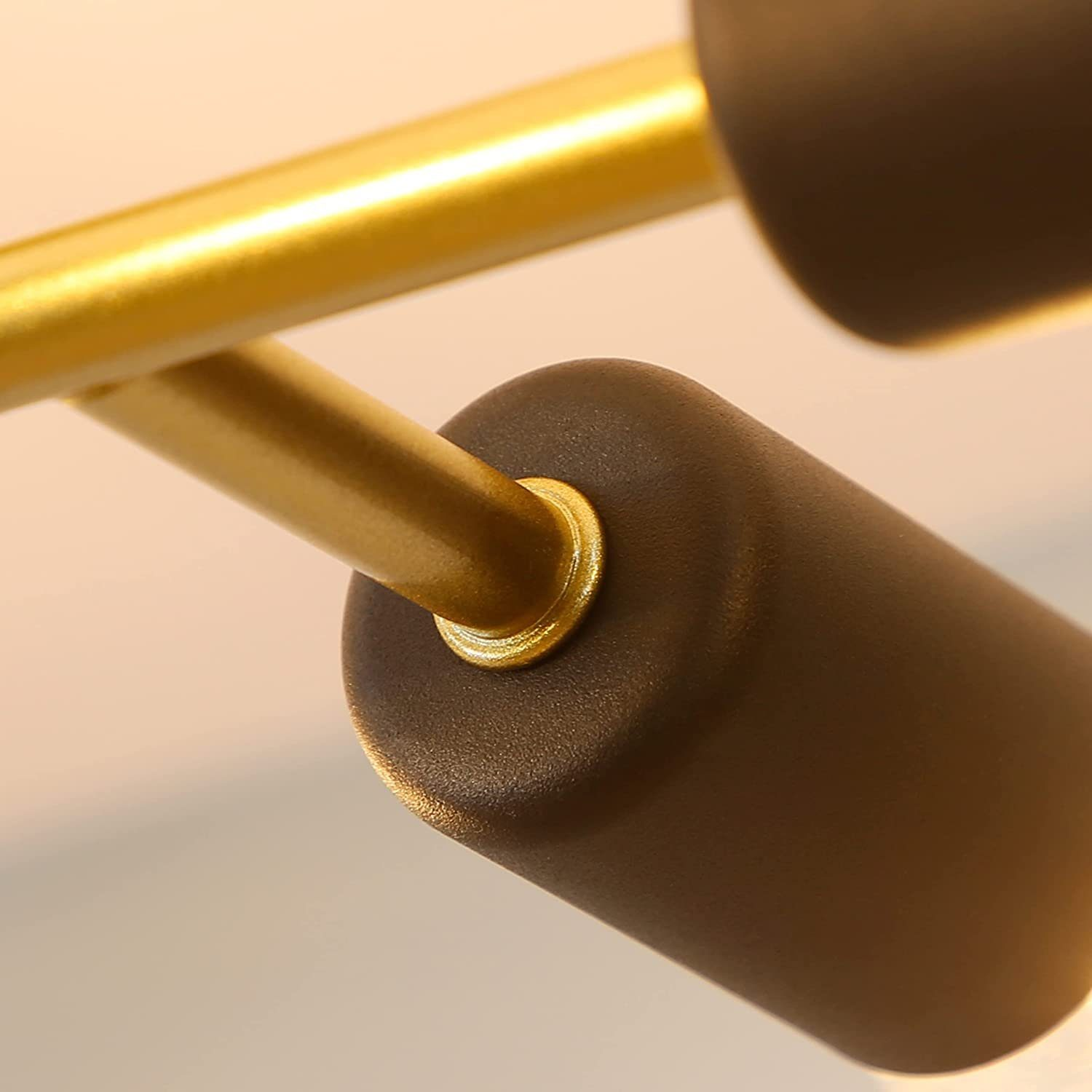 Zbliżenie reflektora. Oprawa oświetleniowa jest czarna i cylindryczna, ze złotym ramieniem.