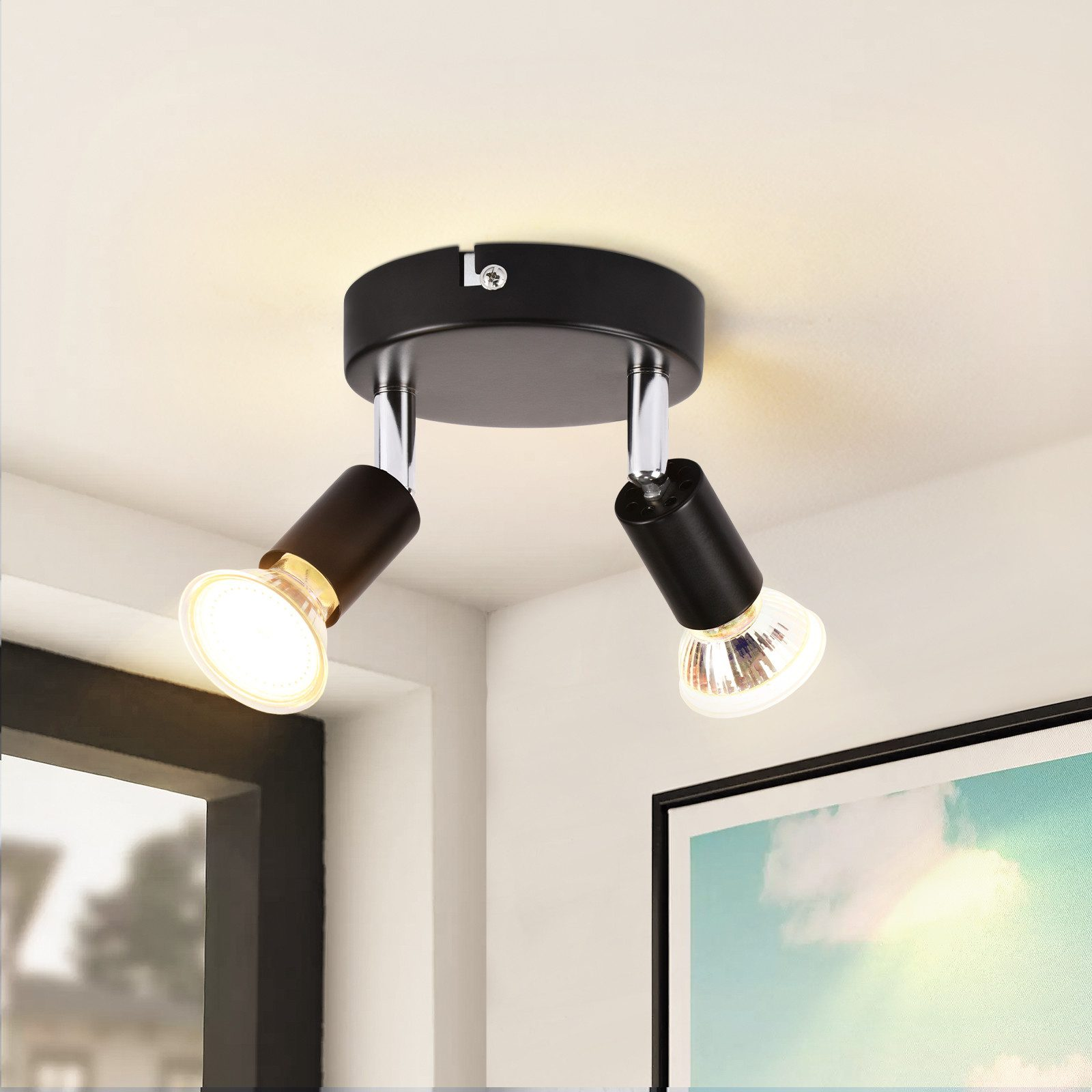 Sufit z dwoma czarnymi reflektorami. Jedno światło jest włączone, drugie wyłączone, obok obrazu.