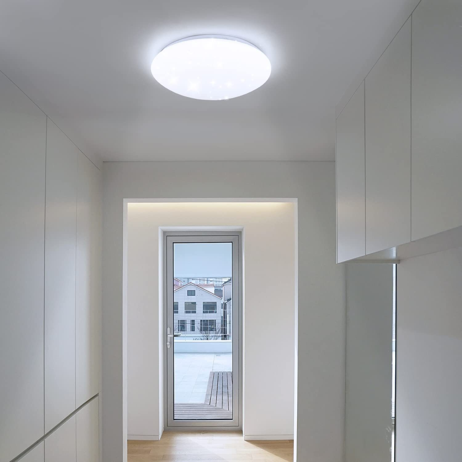 Biała okrągła lampa sufitowa w białym korytarzu z drzwiami.