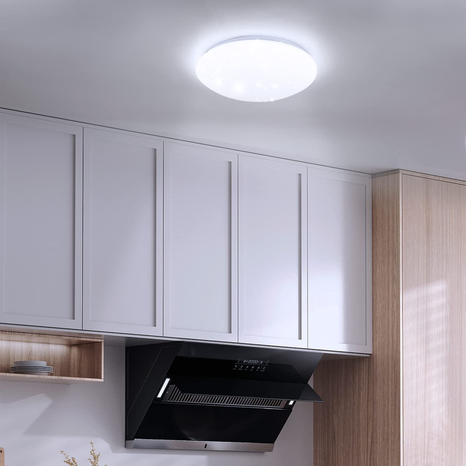 Kuchnia z białymi szafkami, czarnym okapem i lampą sufitową.