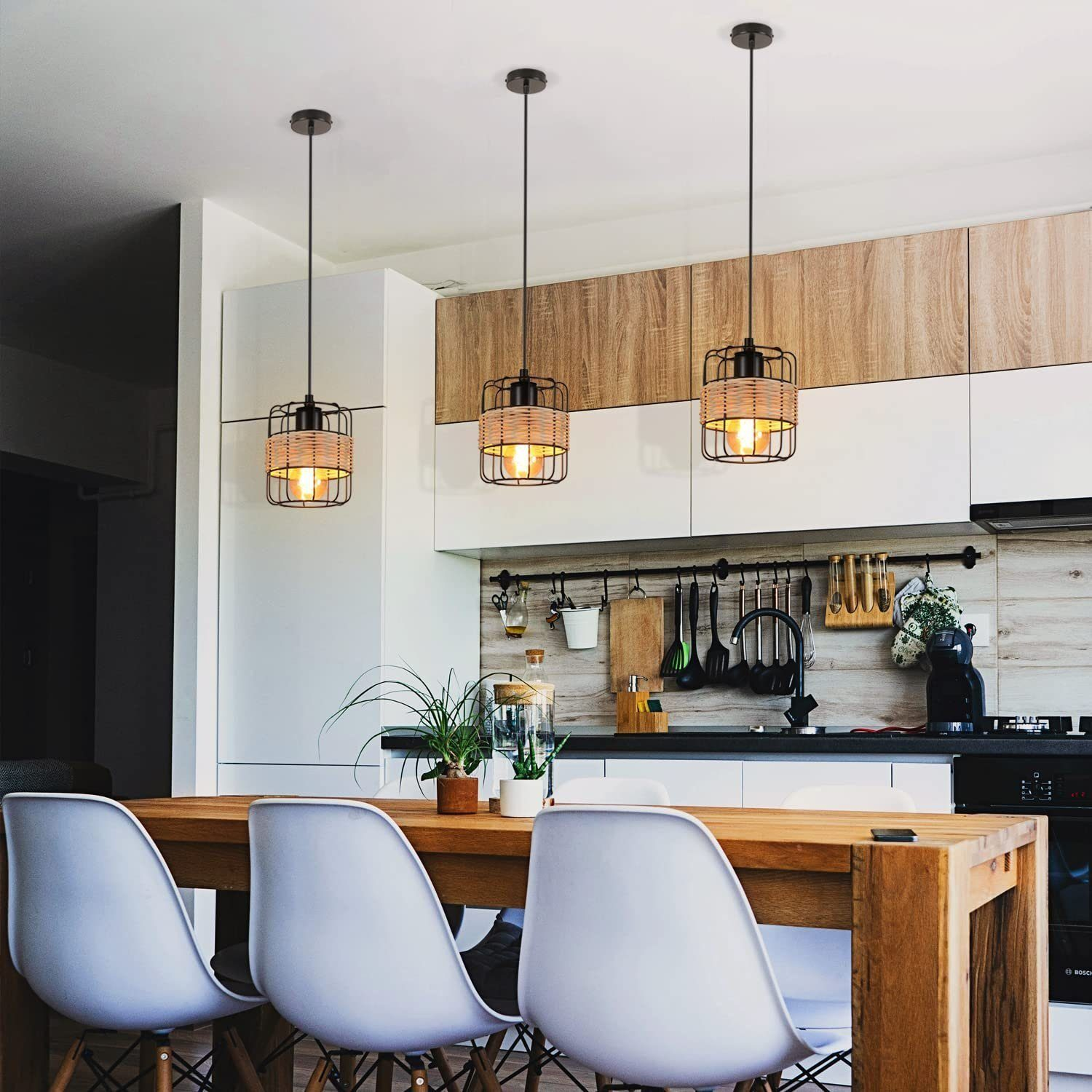 Kuchnia z trzema lampami wiszącymi. Drewniany stół z białymi krzesłami. Tło: białe szafki, drewniana ściana.