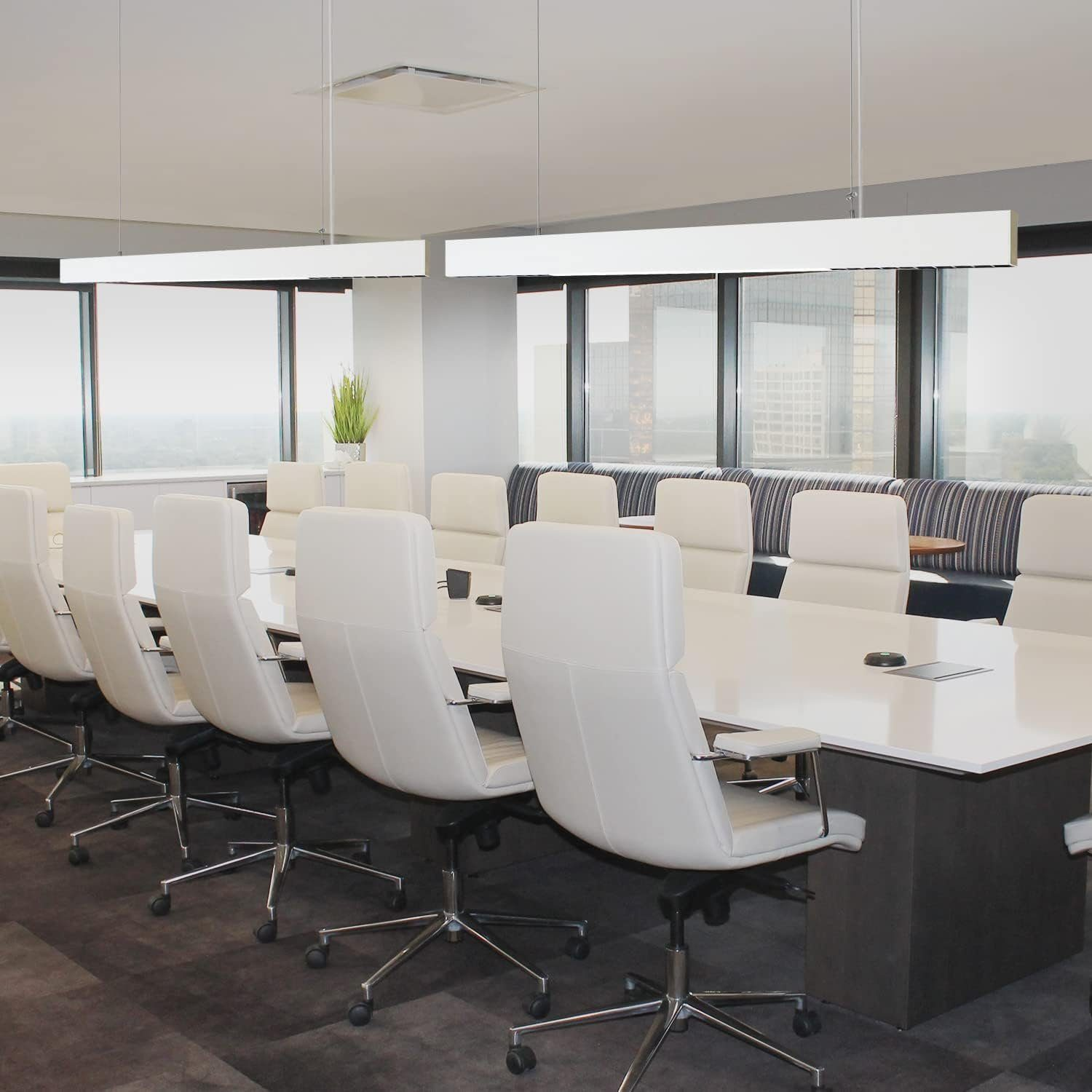 Ein moderner Bürokonferenzraum mit einem langen weißen Tisch, weißen Stühlen und großen Fenstern.