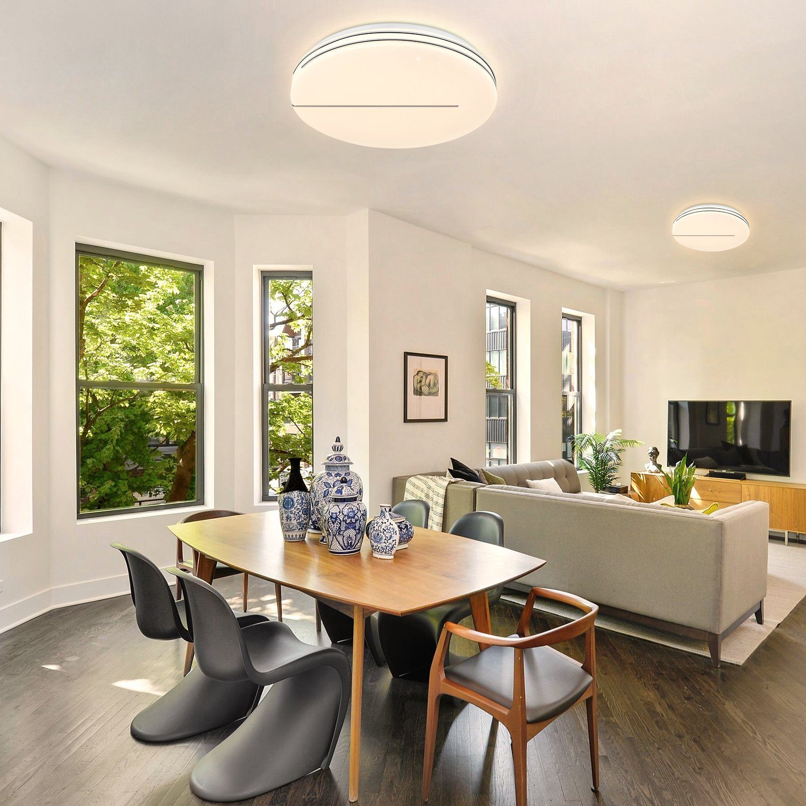 Jadalnia z dwoma lampami sufitowymi, stołem, krzesłami i dużym oknem.