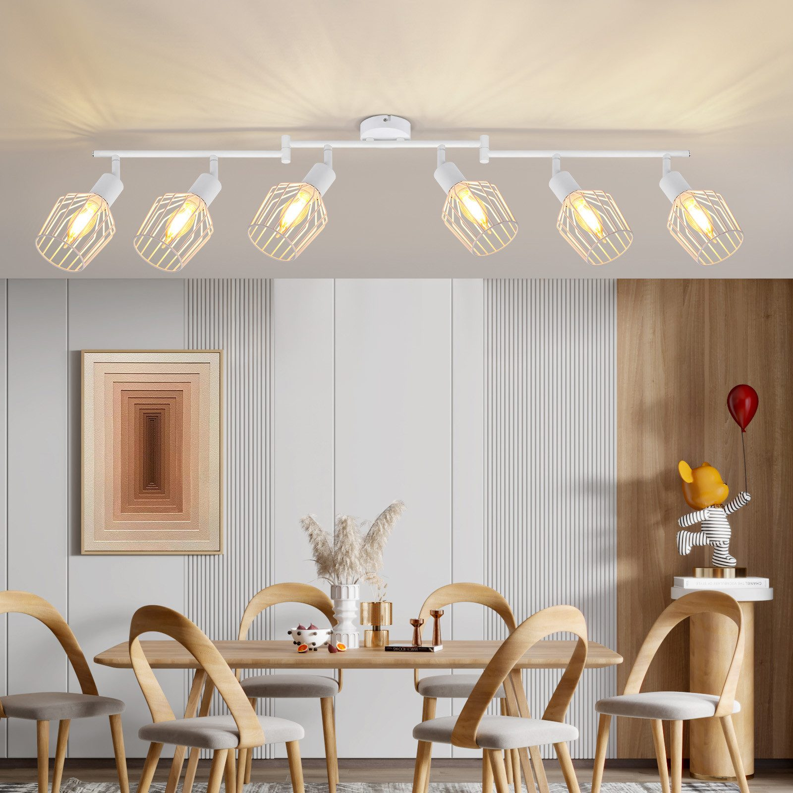 Sala da pranzo con illuminazione a binario bianca, sei sedie e opere d'arte incorniciate. Palloncini e una figura.