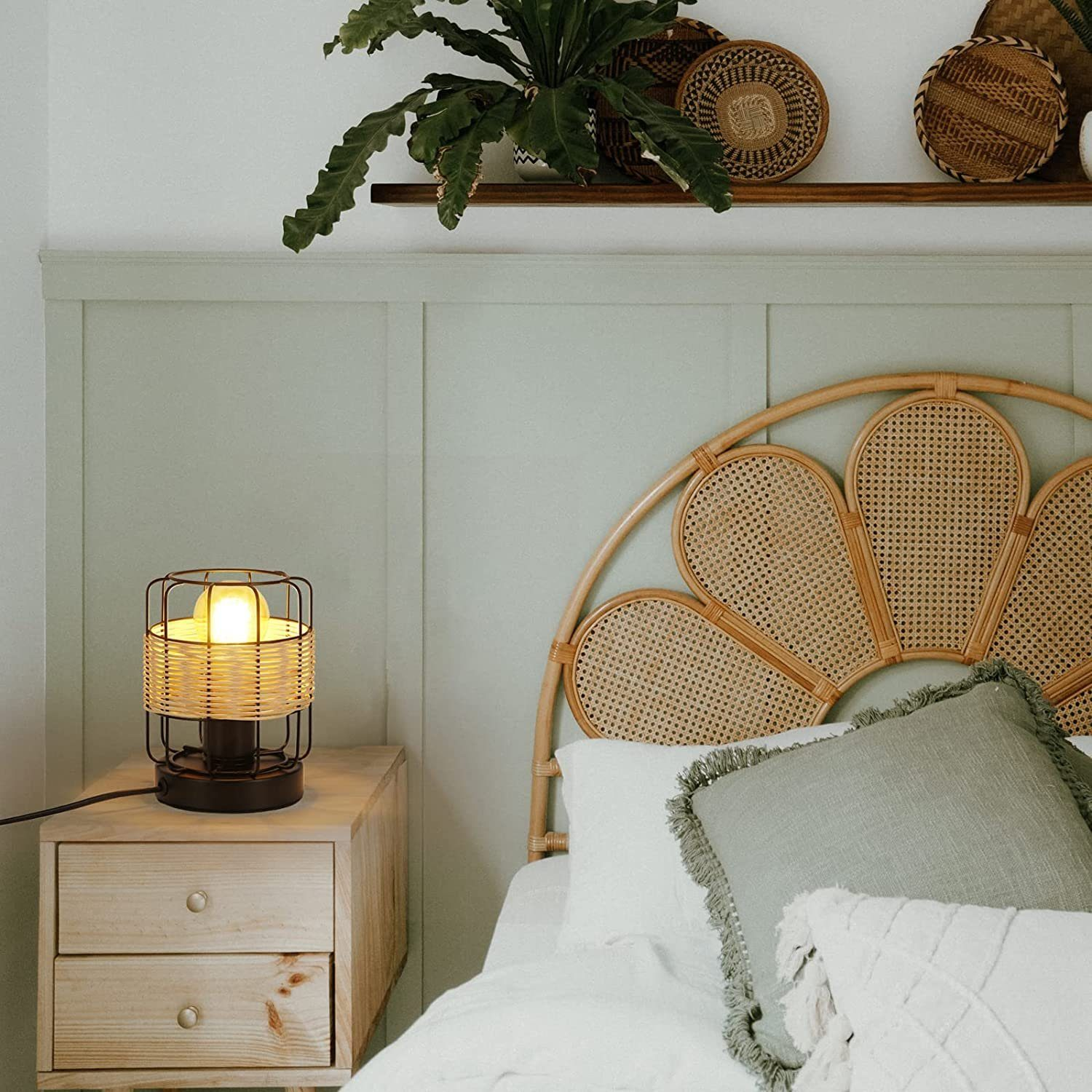 Scena przy łóżku z lampą, drewnianą szafką nocną, łóżkiem z poduszkami i rattanowym wezgłowiem.