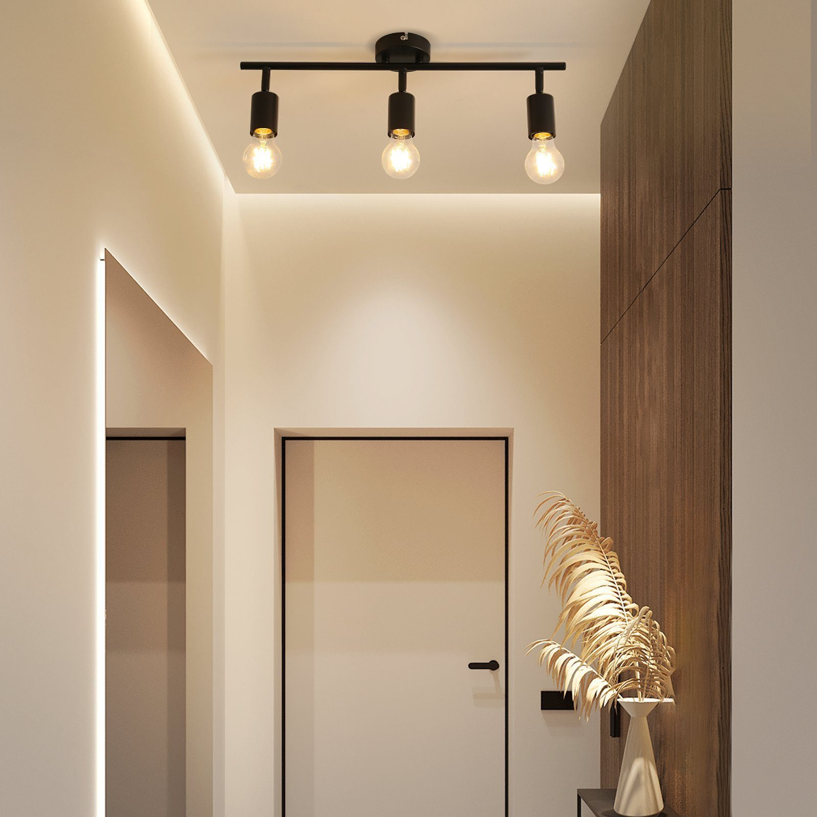 Trzy żarówki w oprawie sufitowej na korytarzu. Białe drzwi, neutralne ściany i roślina dekoracyjna.