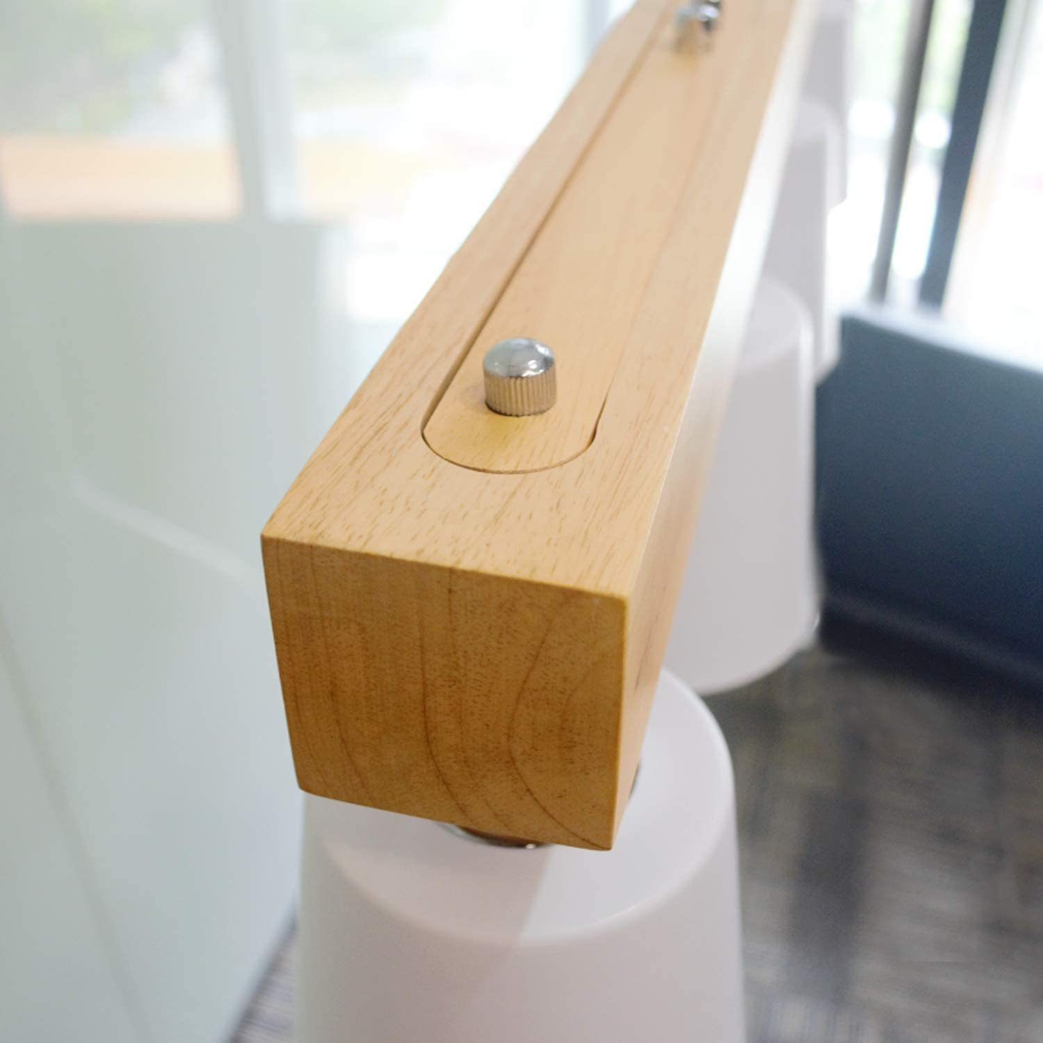 Drewniana belka z metalowym kołkiem i białą podstawą. Jest częścią oprawy oświetleniowej.