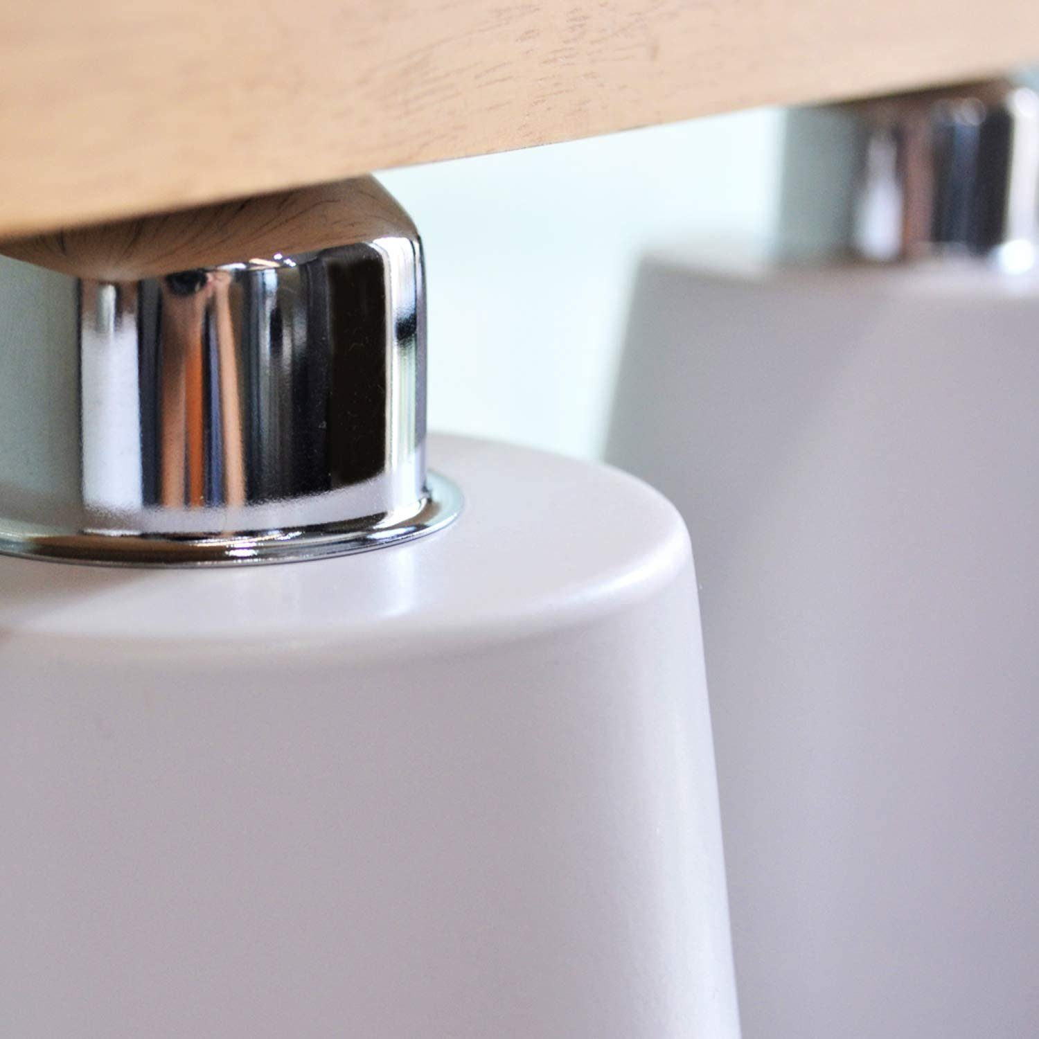 Zbliżenie metalowej podstawy lampy. Podstawa jest biała ze srebrnym metalicznym wykończeniem.