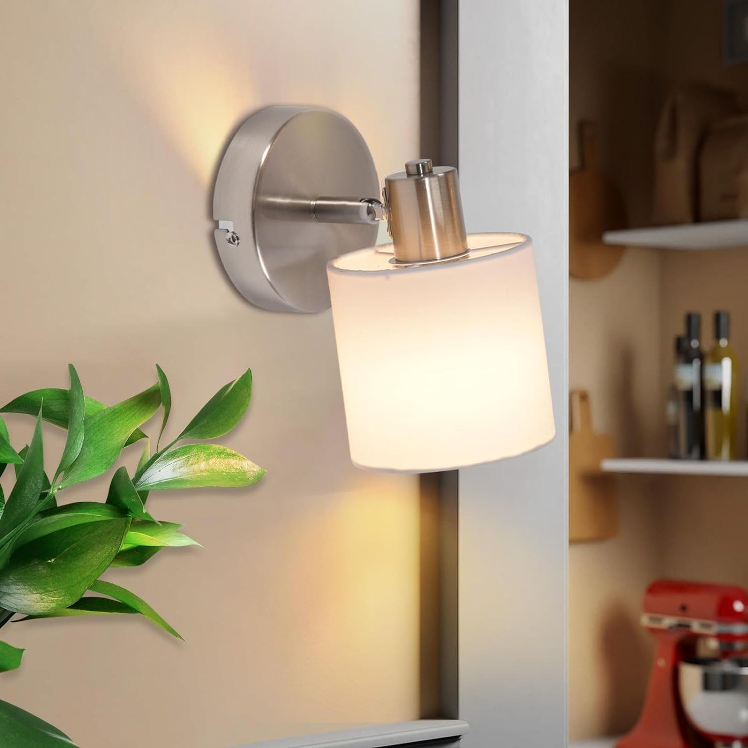 Lampa ścienna z cylindrycznym kloszem. Widoczna zielona roślina i czerwony mikser.