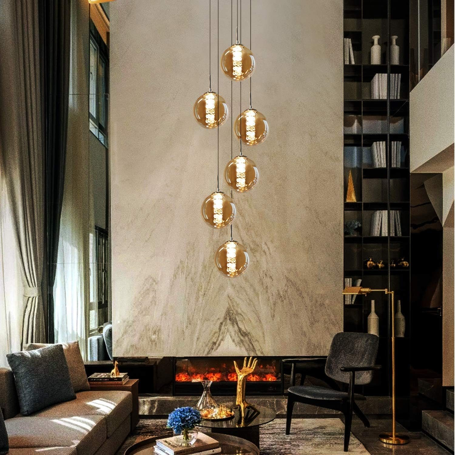 Żyrandol z sześcioma kulistymi światłami wisi nad kominkiem w nowoczesnym salonie.