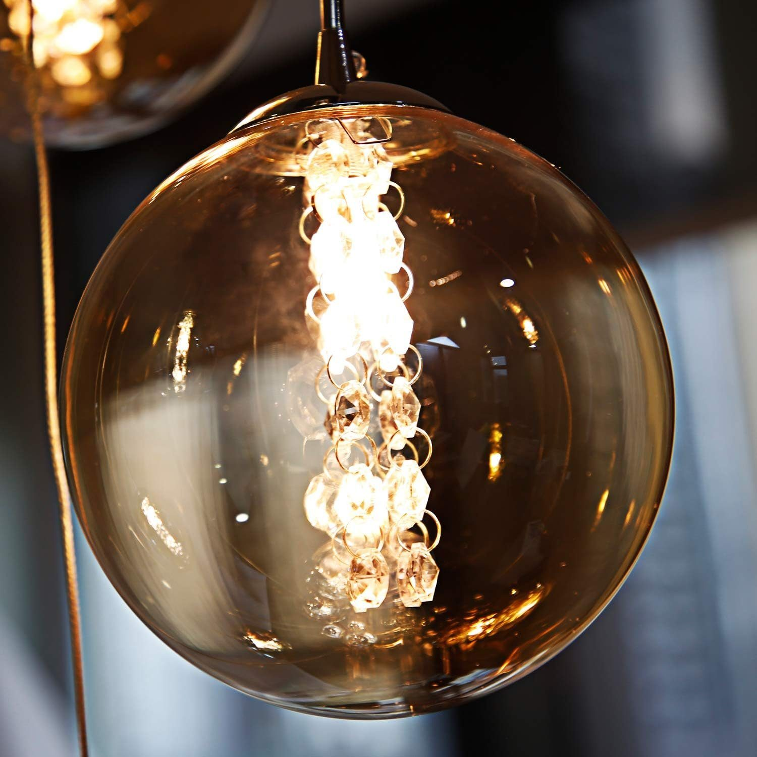 Zbliżenie przezroczystego żyrandola z kulami szklanymi z kryształami w środku.