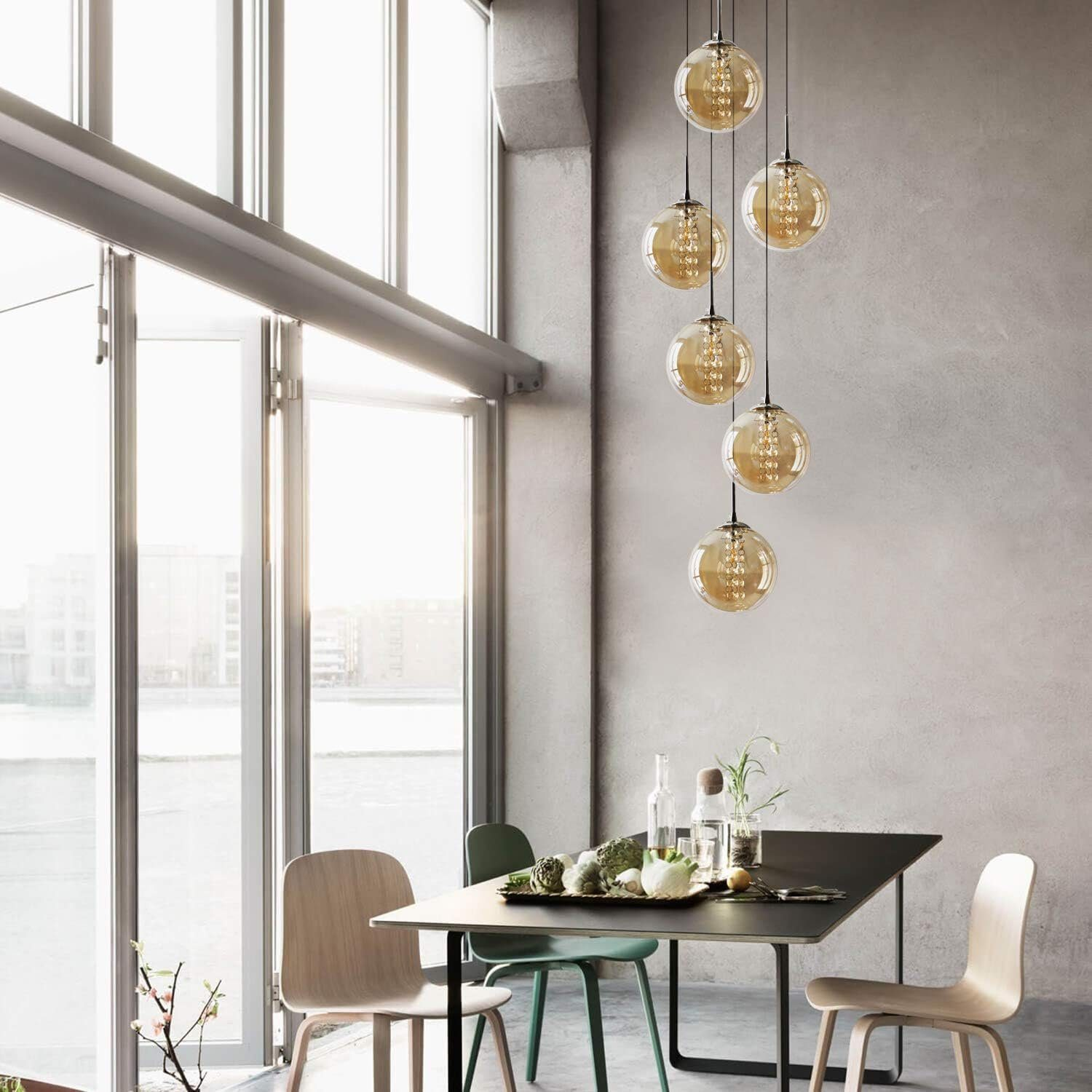 Jadalnia ze stołem i krzesłami. Z sufitu zwisa kilka kulistych, bursztynowych świateł.