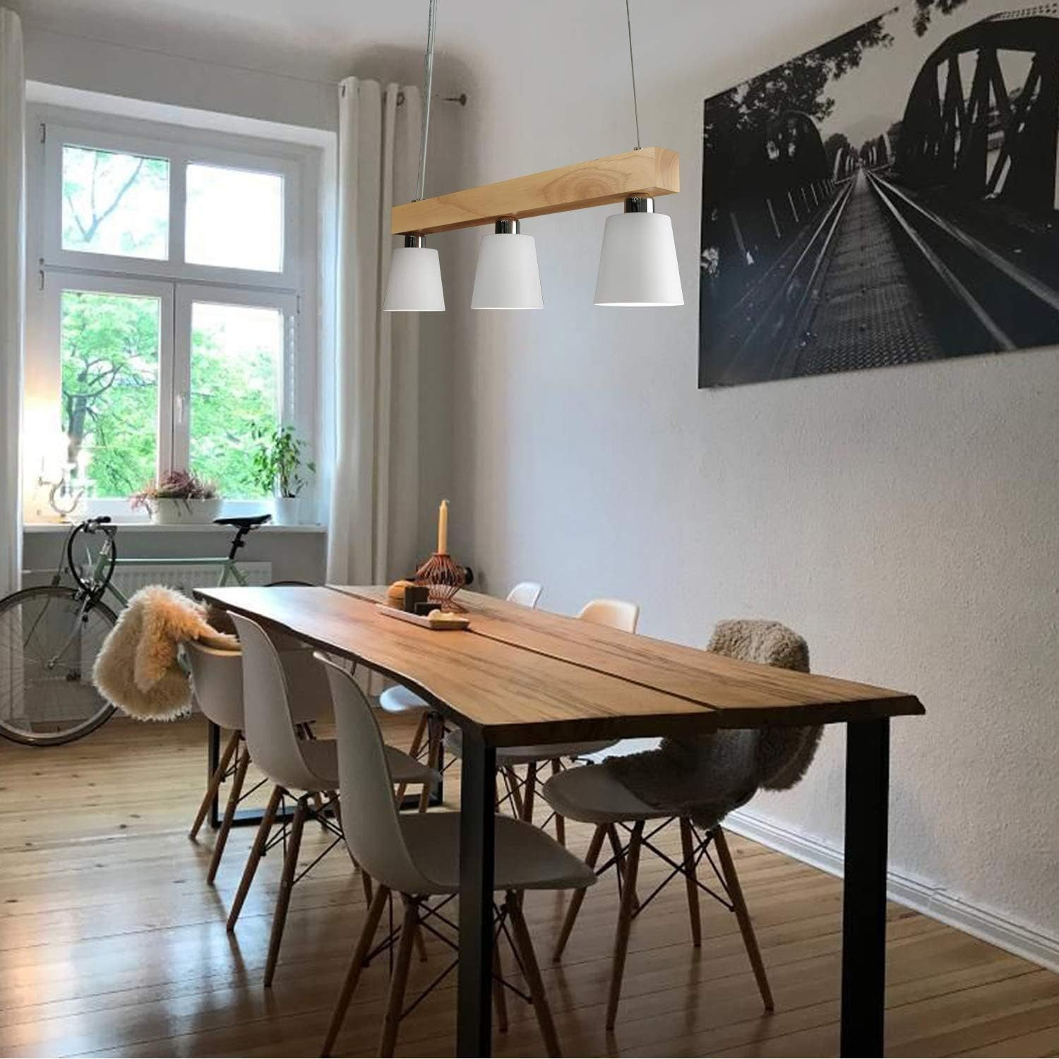 Una sala da pranzo con un tavolo di legno, sedie e una trave di legno chiaro con luci a sospensione bianche.
