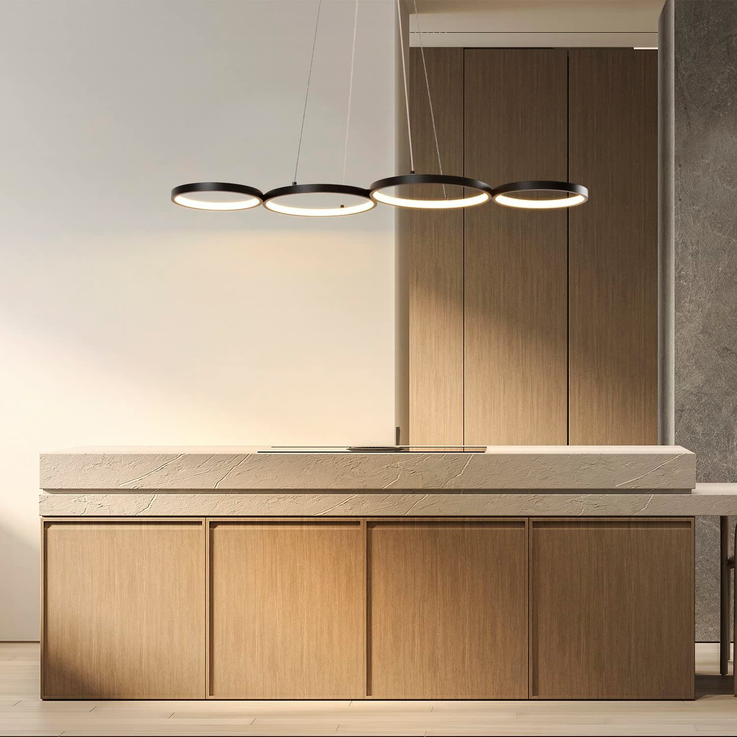 Scena kuchenna z wiszącymi czarnymi lampami pierścieniowymi nad wyspą. Drewniane szafki i blat w tle.