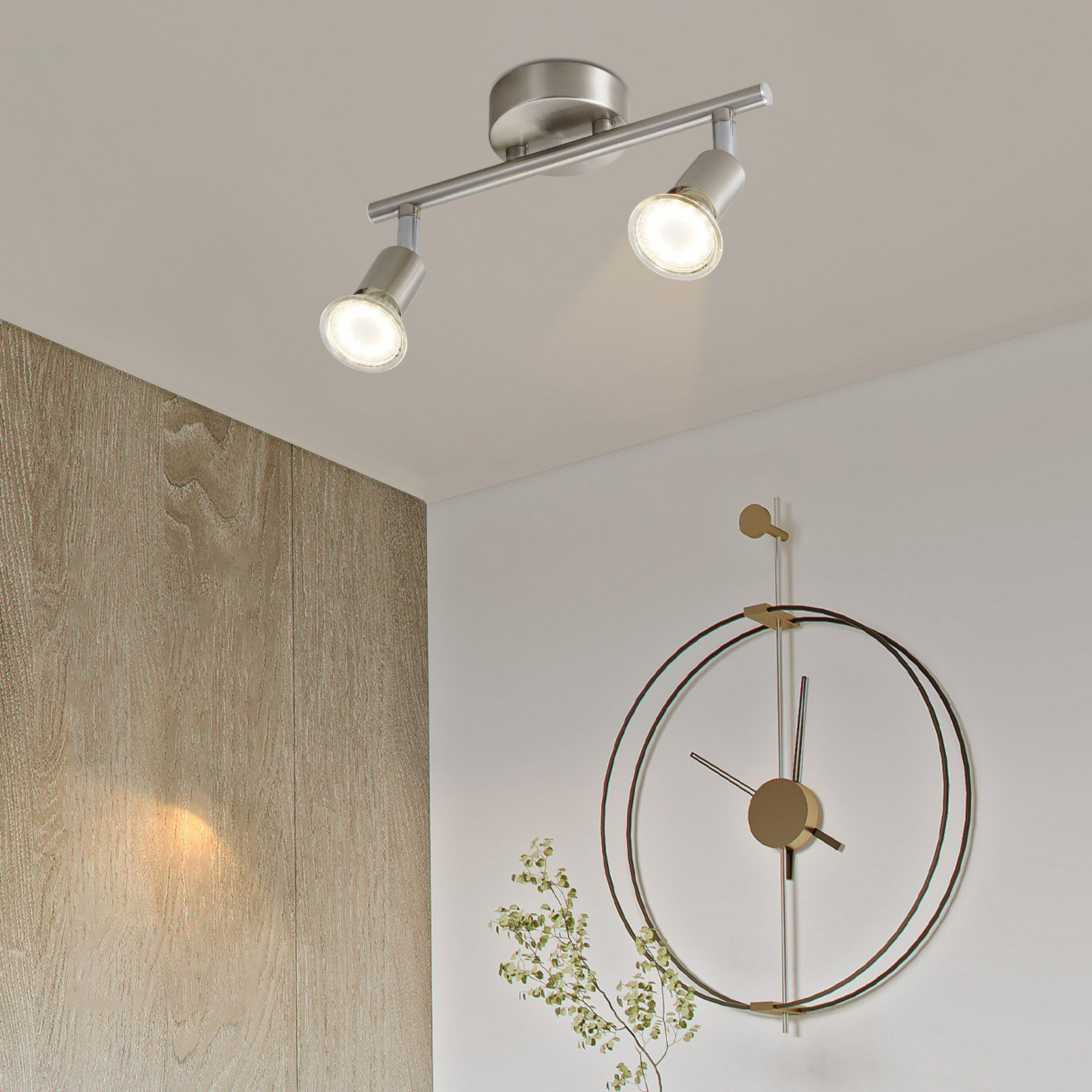 Dwa reflektory na metalowym pręcie na suficie. Na ścianie wisi zegar.