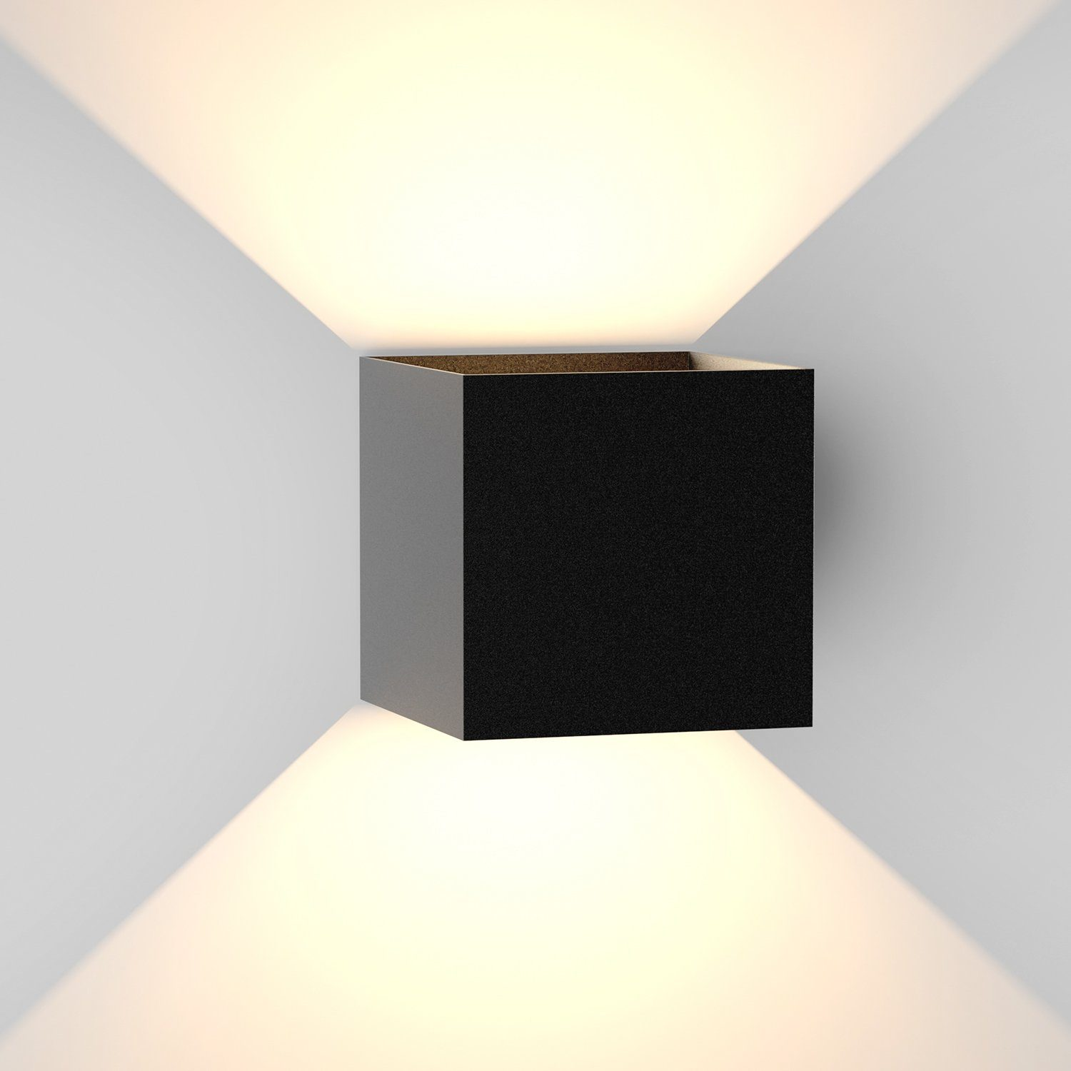 Applique a forma di cubo nero che emette luce verso l'alto e verso il basso su un muro bianco.