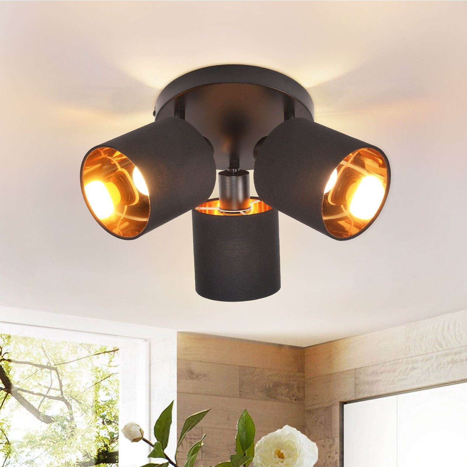 Tre faretti da soffitto neri con interni dorati. Sono disposti in un design circolare con la luce accesa.