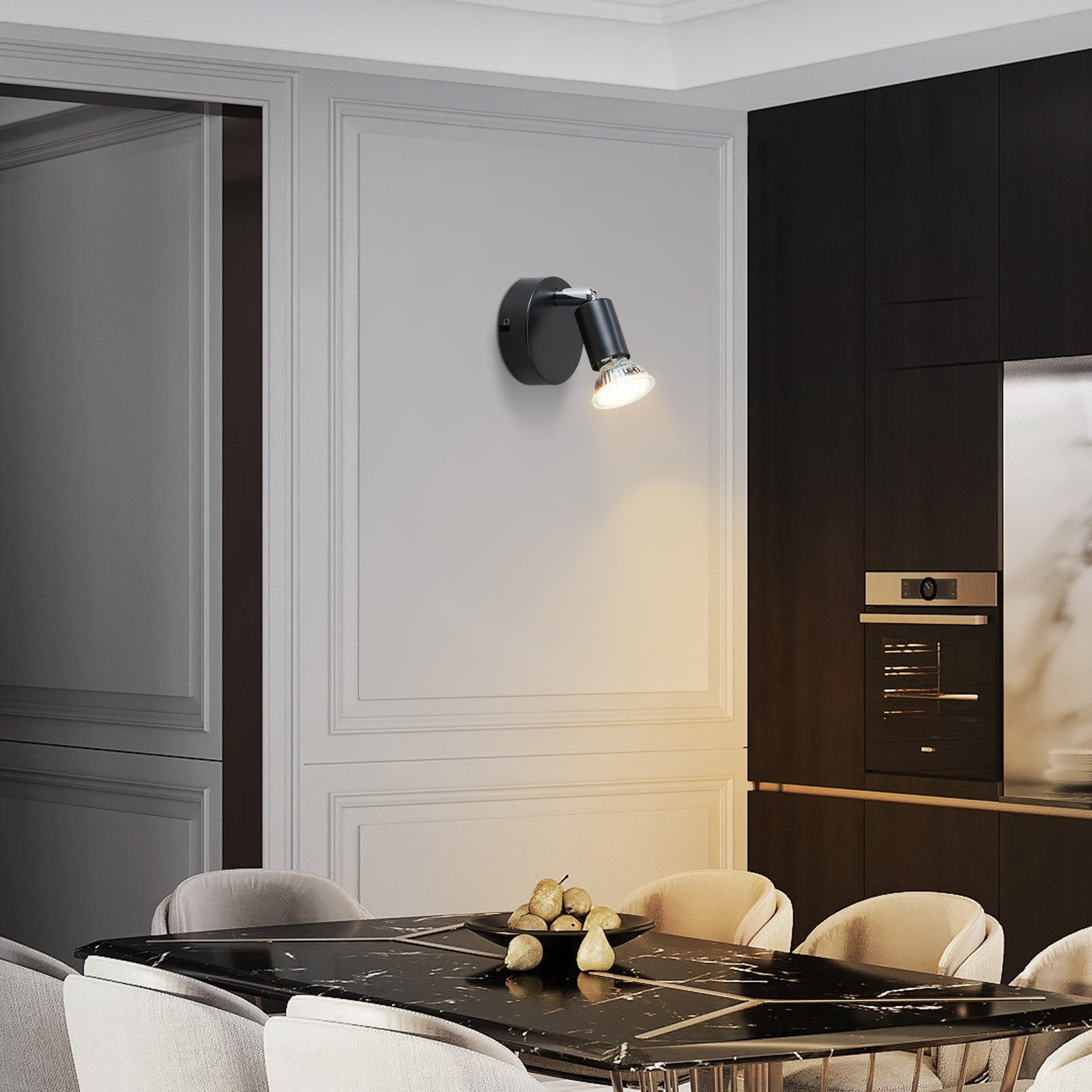 Czarna lampa ścienna jest włączona. Światło oświetla czarny marmurowy stół na pierwszym planie.