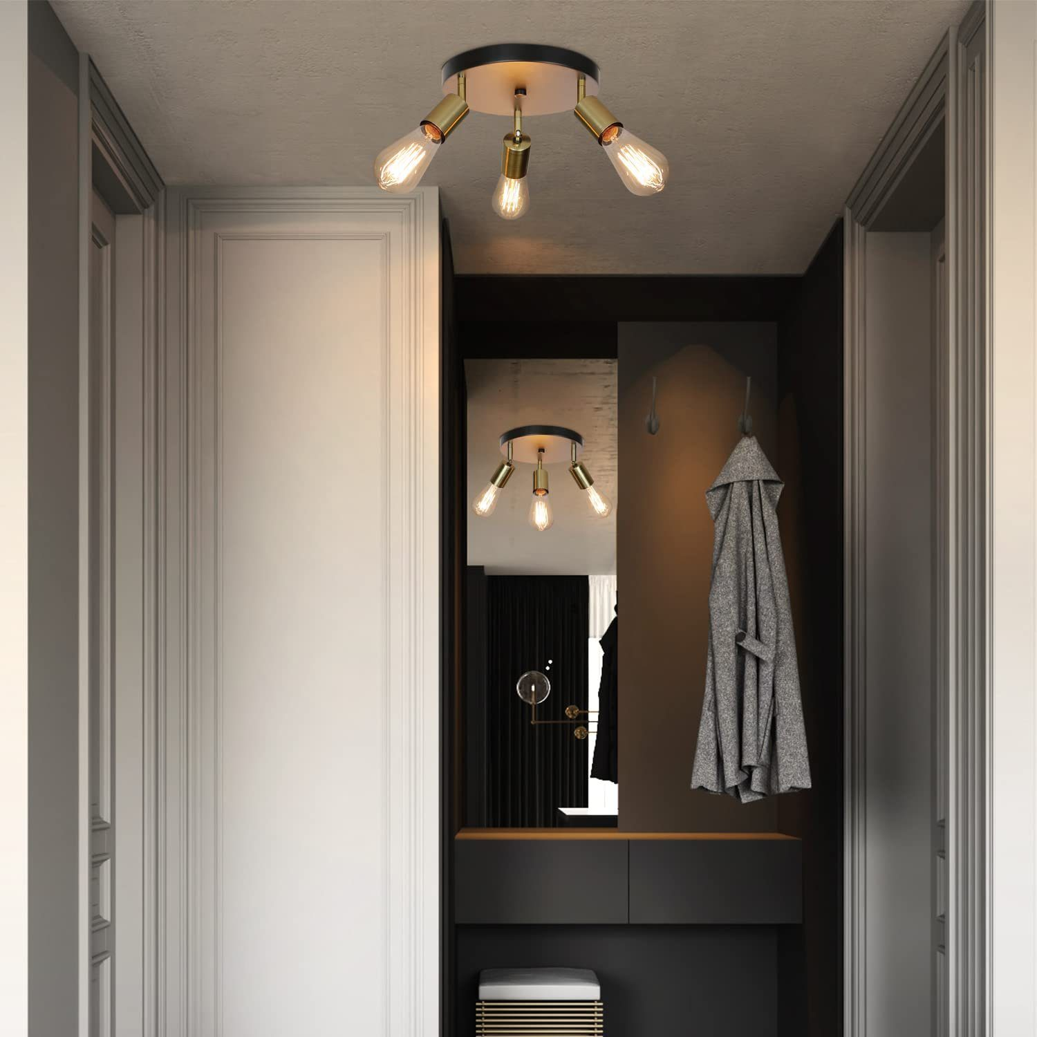 Un corridoio moderno illuminato da un lampadario a soffitto con più lampadine rivolte verso il basso, riflesse in uno specchio.