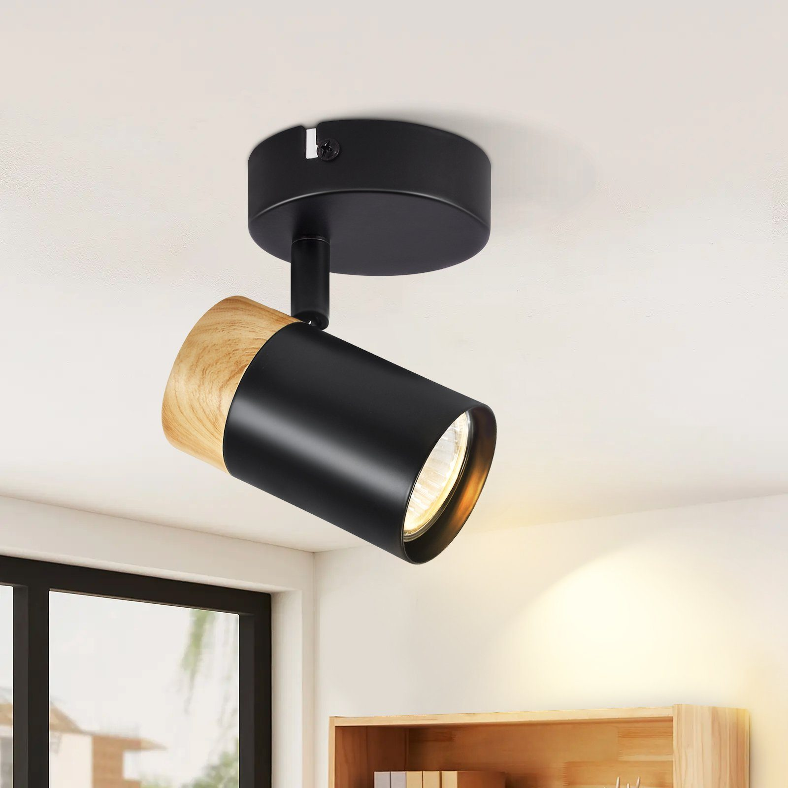 Un faretto da soffitto nero e con accenti in legno. La lampadina è accesa.