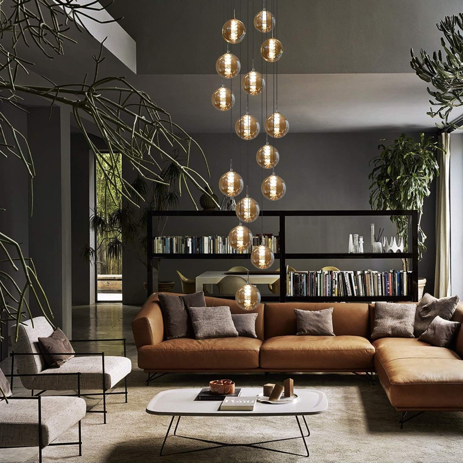 Ein modernes Wohnzimmer mit einem Kronleuchter aus hängenden Glaskugeln. Sofa, Pflanzen und Regale sind sichtbar.