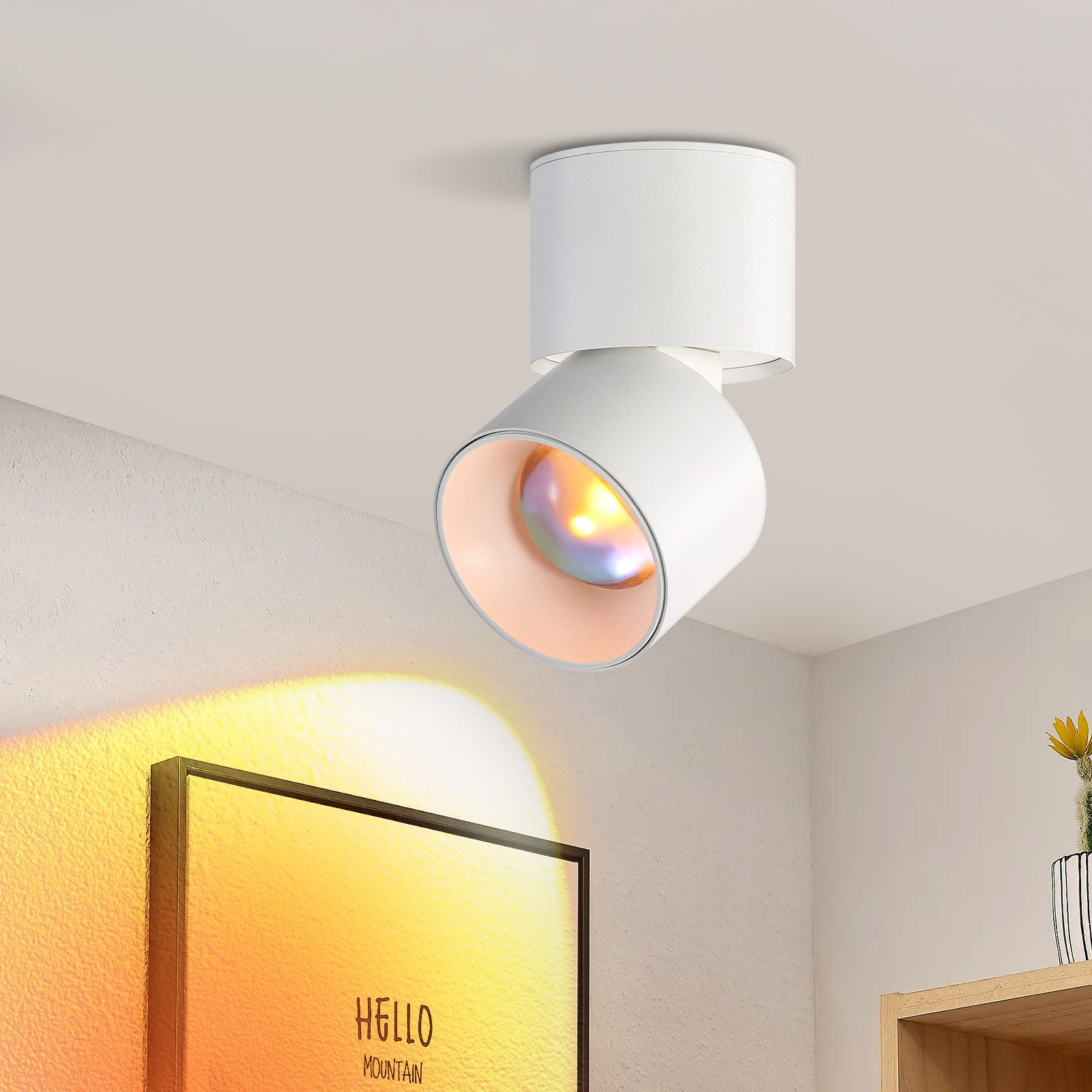 Faretto bianco a soffitto, angolato. Ha un corpo bianco e una luce colorata.