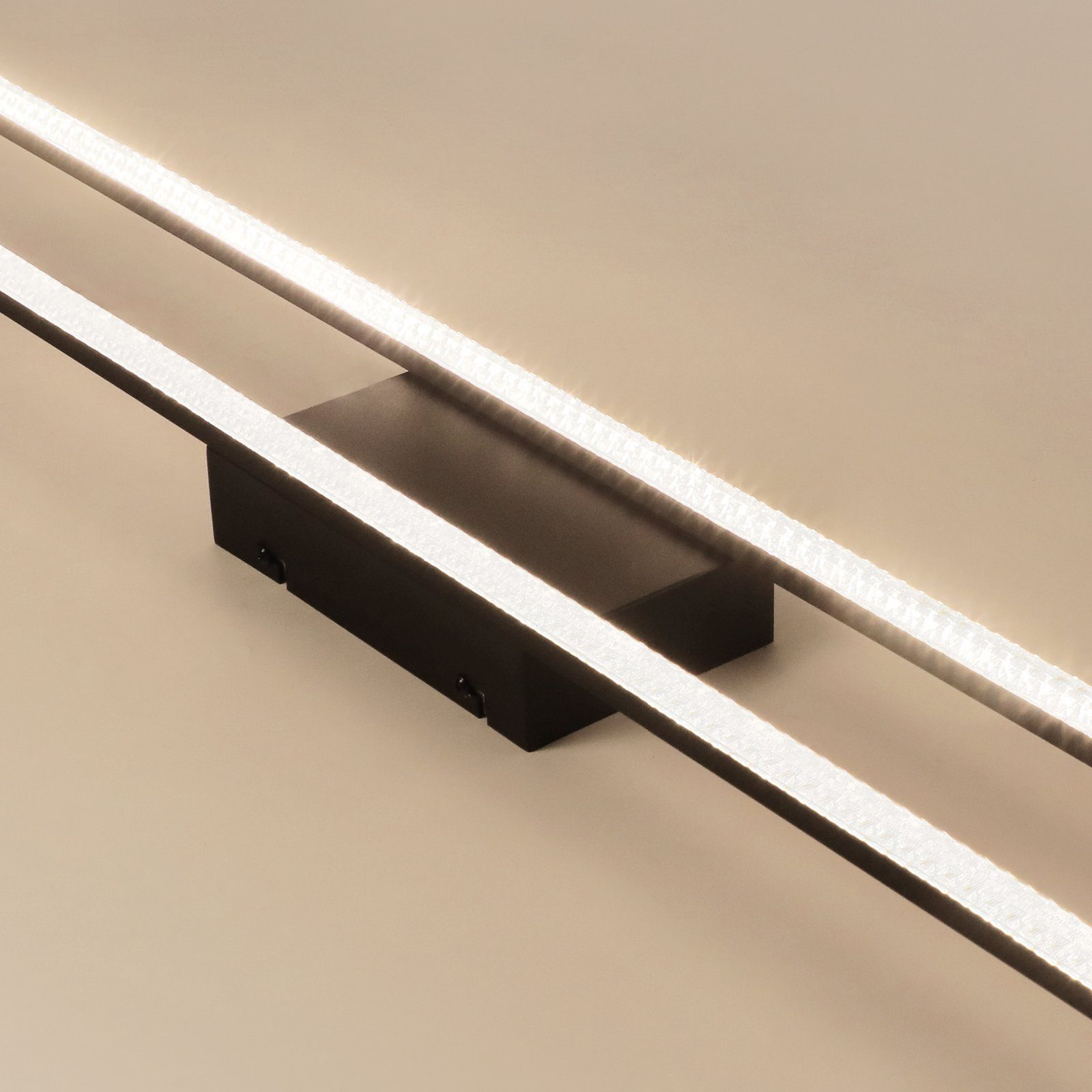 Due strisce luminose a LED parallele montate su una parete. Le luci sono di un bianco brillante e il muro è beige chiaro.