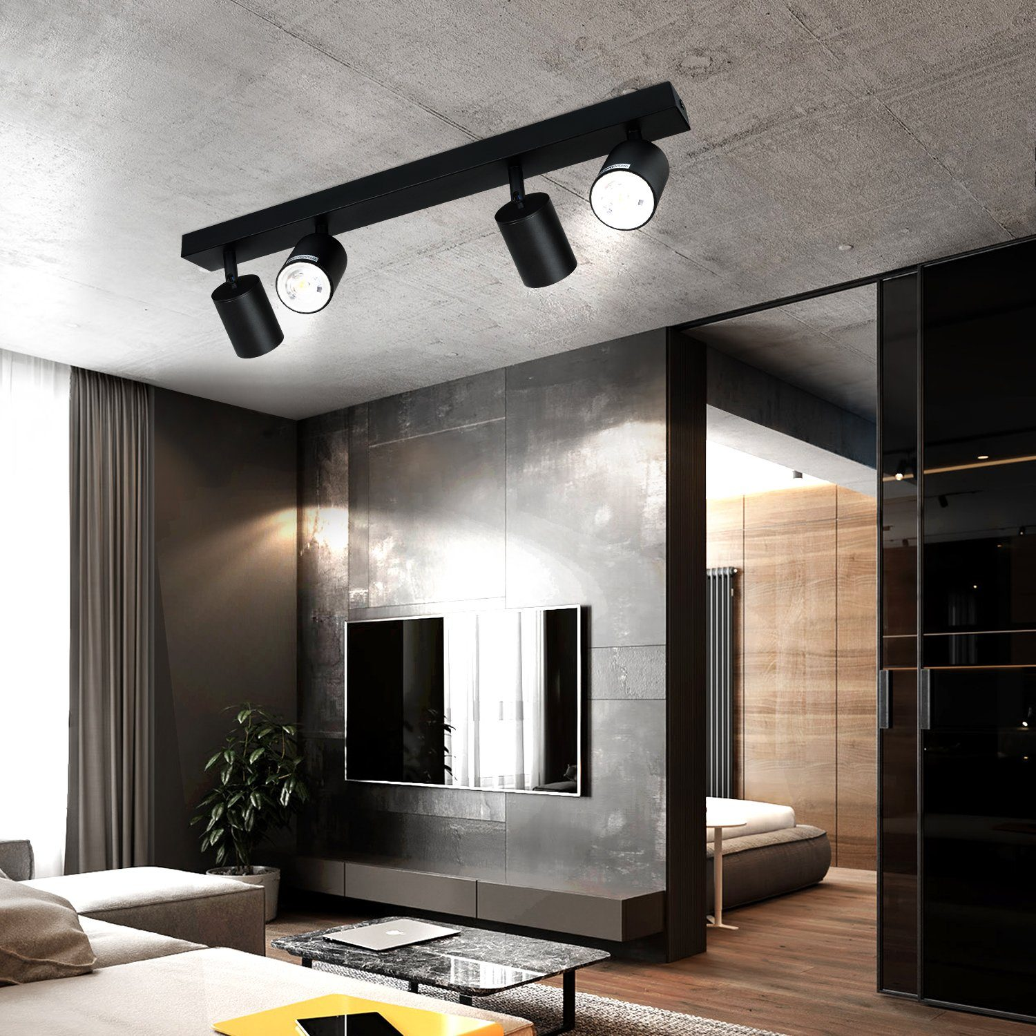 Binario di illuminazione nero con tre faretti regolabili su un soffitto grigio sopra un soggiorno.