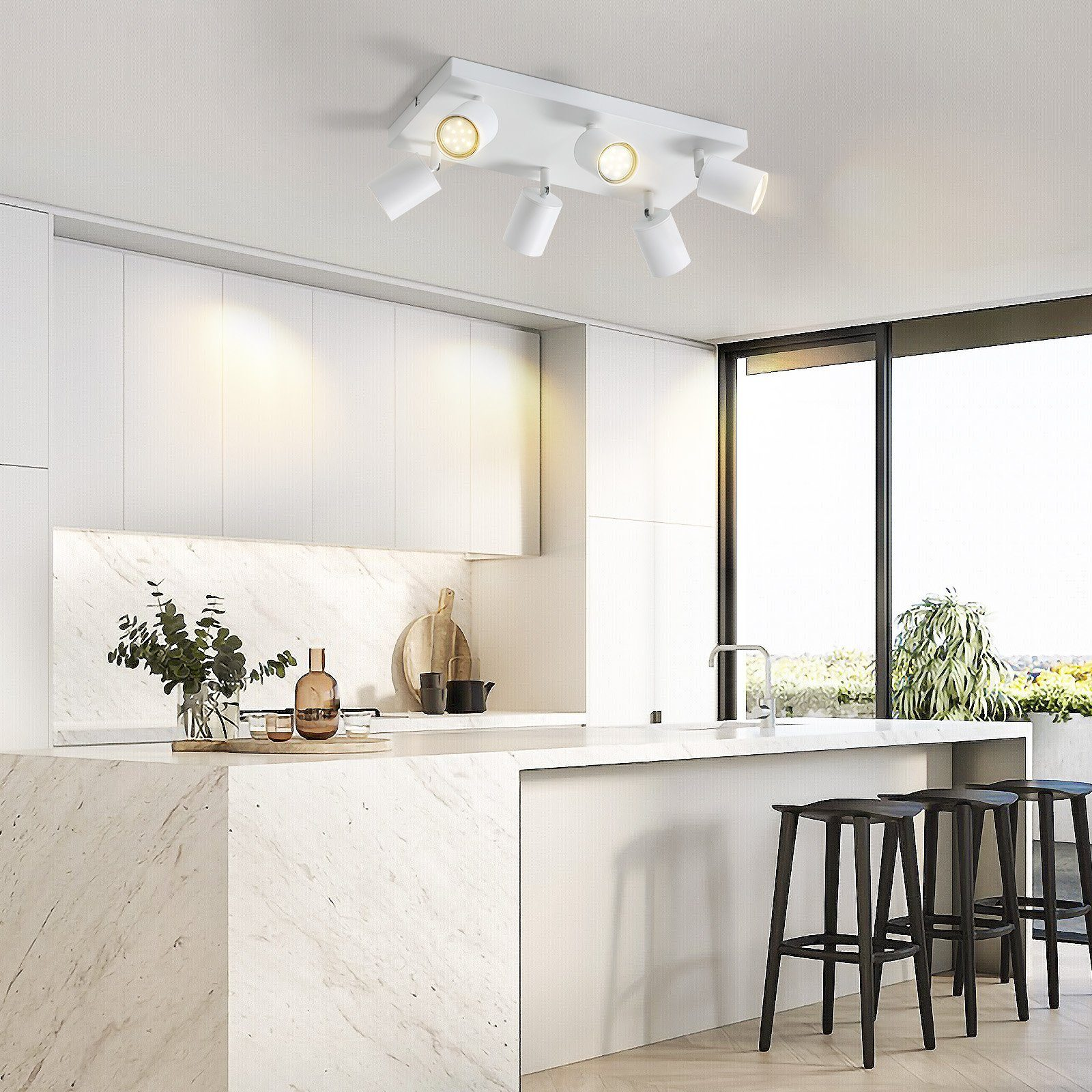 Faretti bianchi a soffitto in una cucina moderna. Cucina con piani di lavoro in marmo e sgabelli neri.