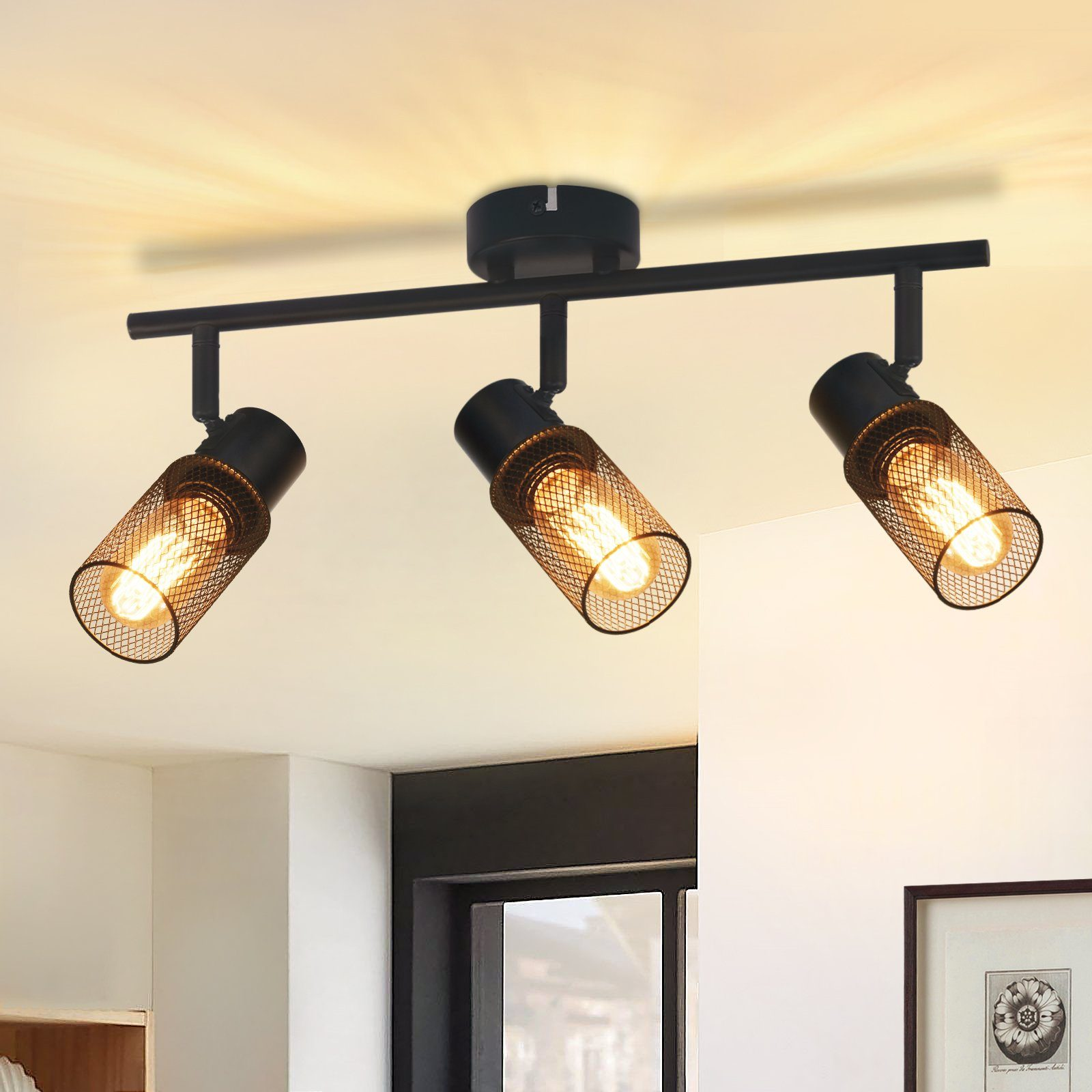Illuminazione a binario nera con tre lampade a rete, che illuminano un soffitto bianco. Stanza con pareti bianche e finestra.