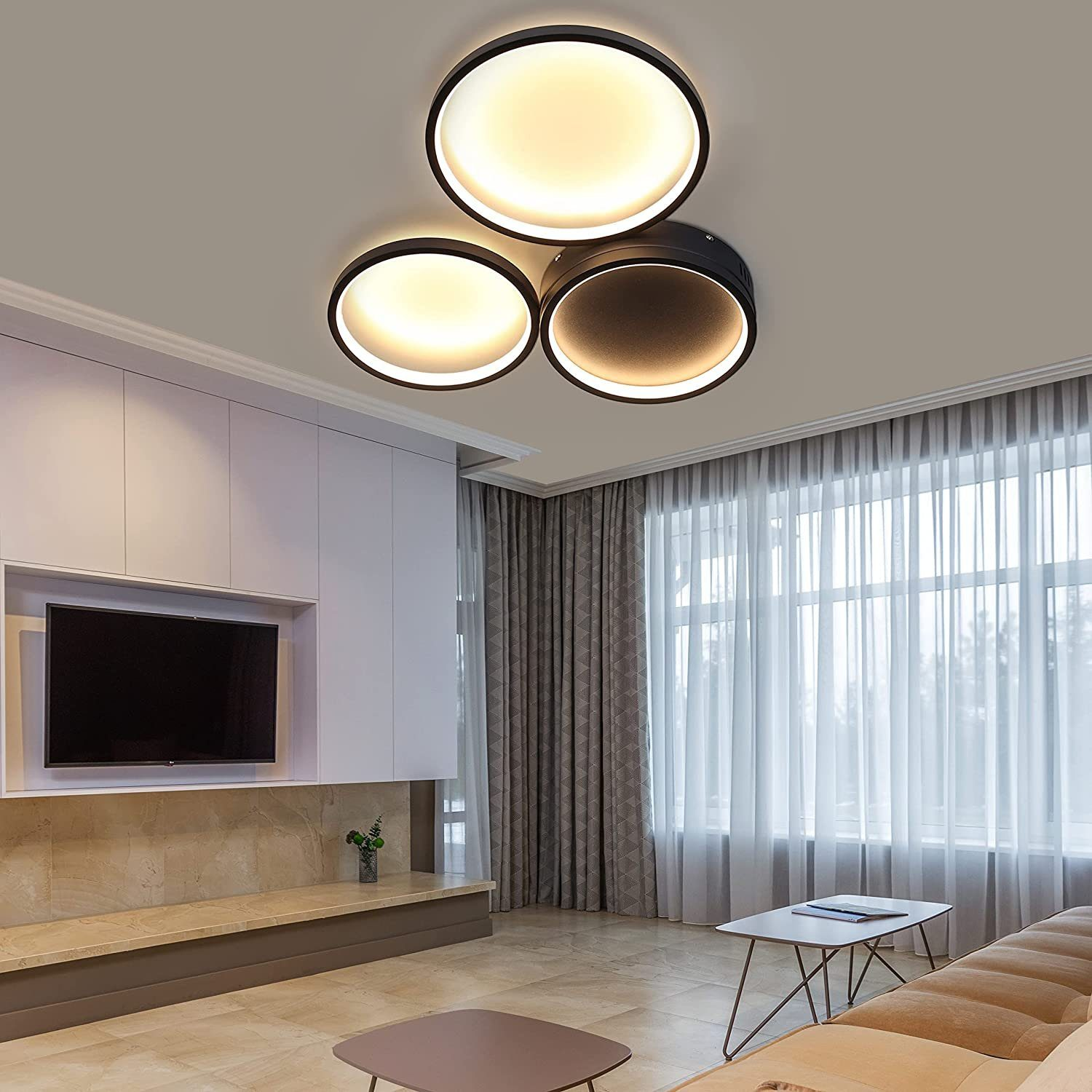 Salon z nowoczesną lampą sufitową. Trzy okrągłe światła są umieszczone w czarnych ramach. Przestrzeń ma wystrój.