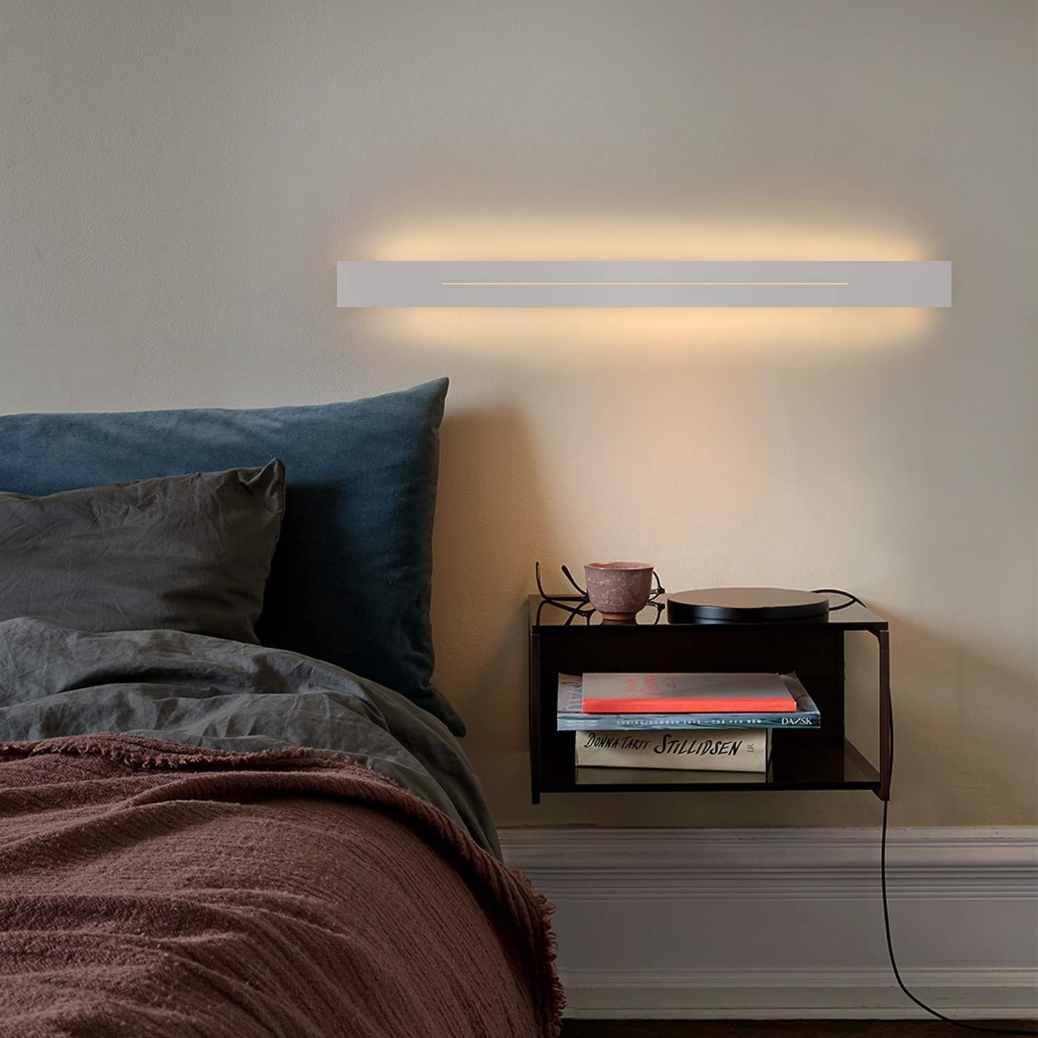 Una scena della camera da letto con un'applique, un letto, un comodino e oggetti decorativi.