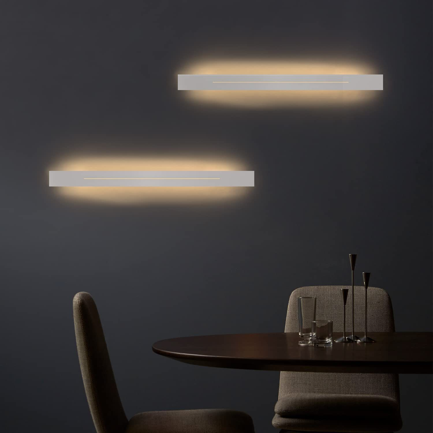 Zwei rechteckige Wandleuchten nebeneinander, an einer dunkelgrauen Wand montiert. Die Lichter strahlen sanft.