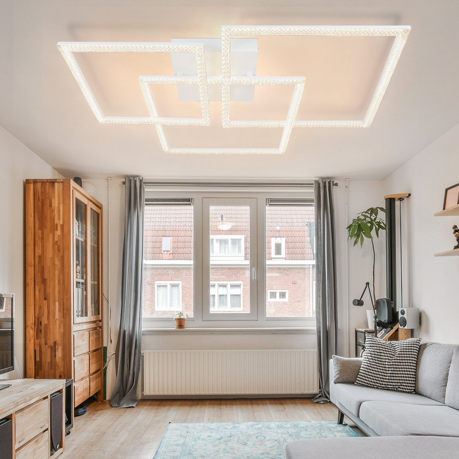 Un'apparecchio di illuminazione a soffitto bianco brillante con un motivo quadrato, che illumina un soggiorno con finestre.