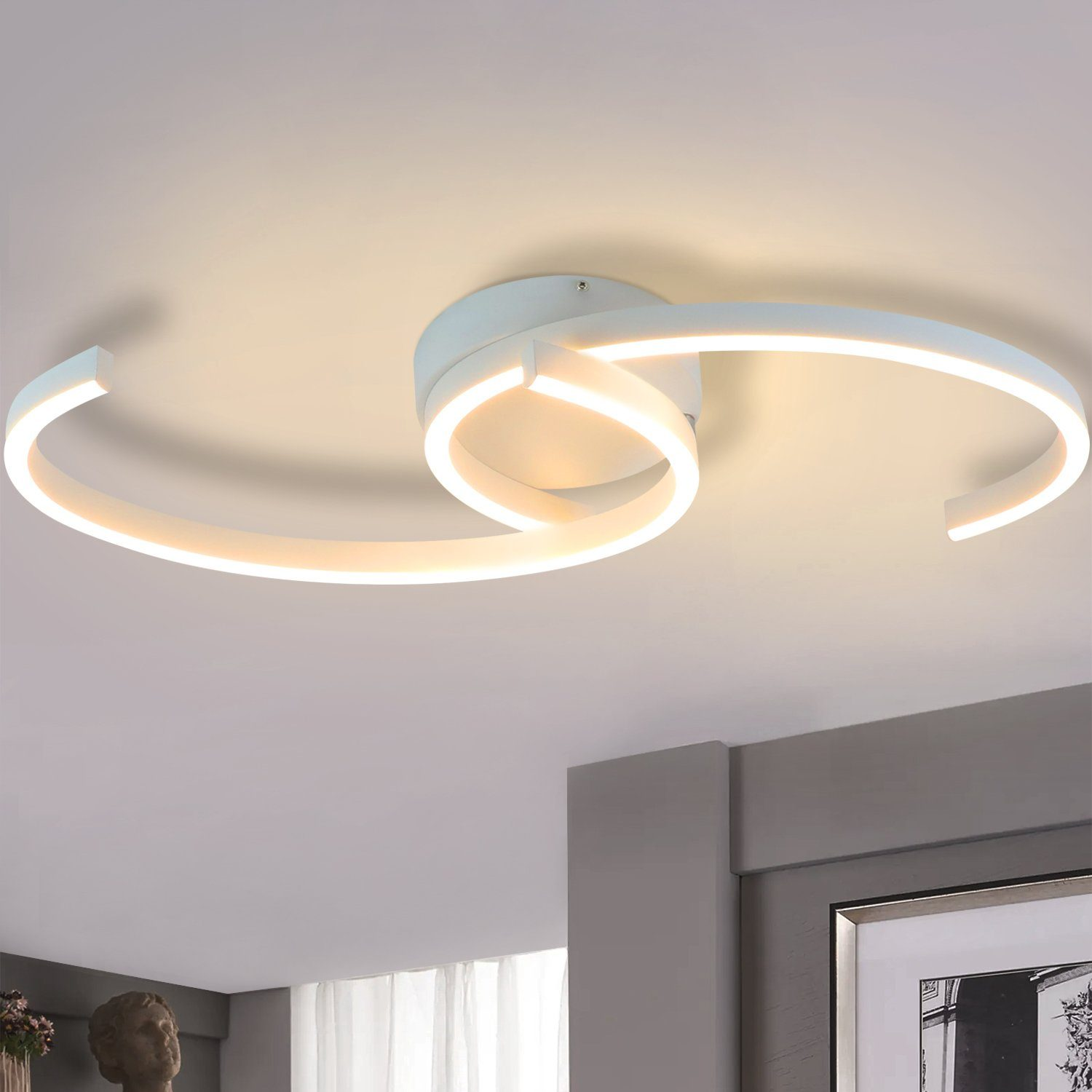 Biała lampa sufitowa o spiralnym designie, podświetlona. Tło: jasny sufit.