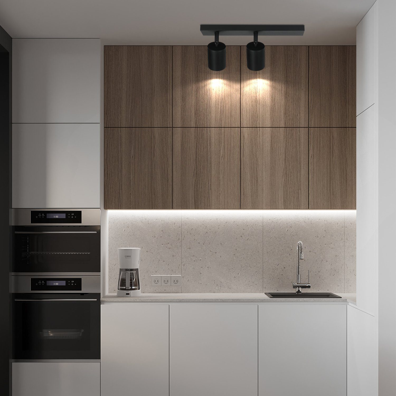 Cucina moderna con due plafoniere nere. Visibili mobili in legno e piani di lavoro bianchi.