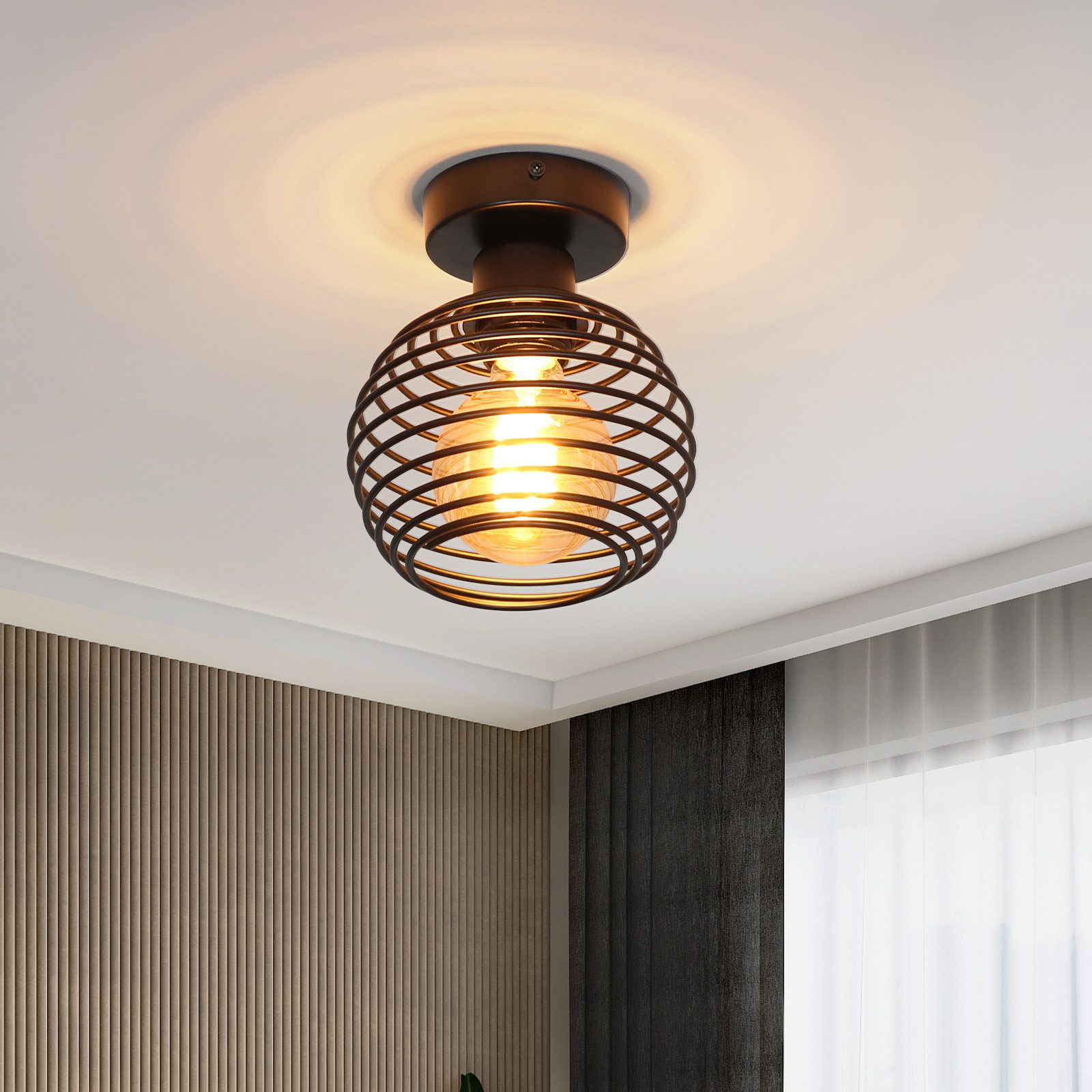 Czarna lampa sufitowa w stylu metalowej klatki z widoczną żarówką, rzucająca światło w dół.