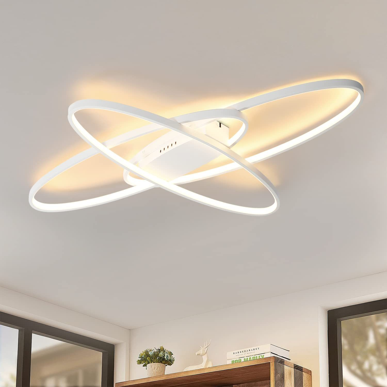 Lampada da soffitto bianca e moderna con ovali intersecanti, che illumina una stanza.