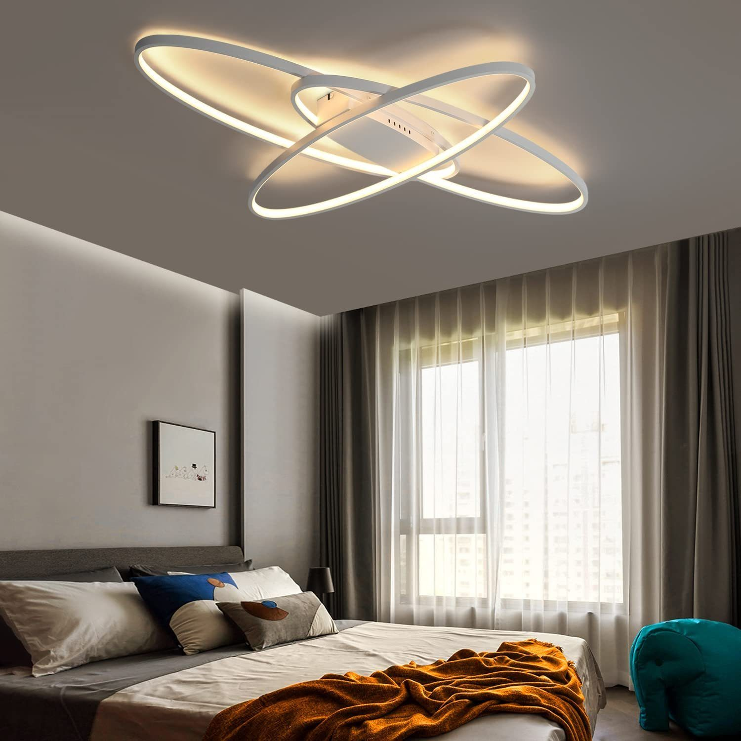 Un apparecchio di illuminazione a soffitto bianco e argento in una camera da letto, con letto e finestra.