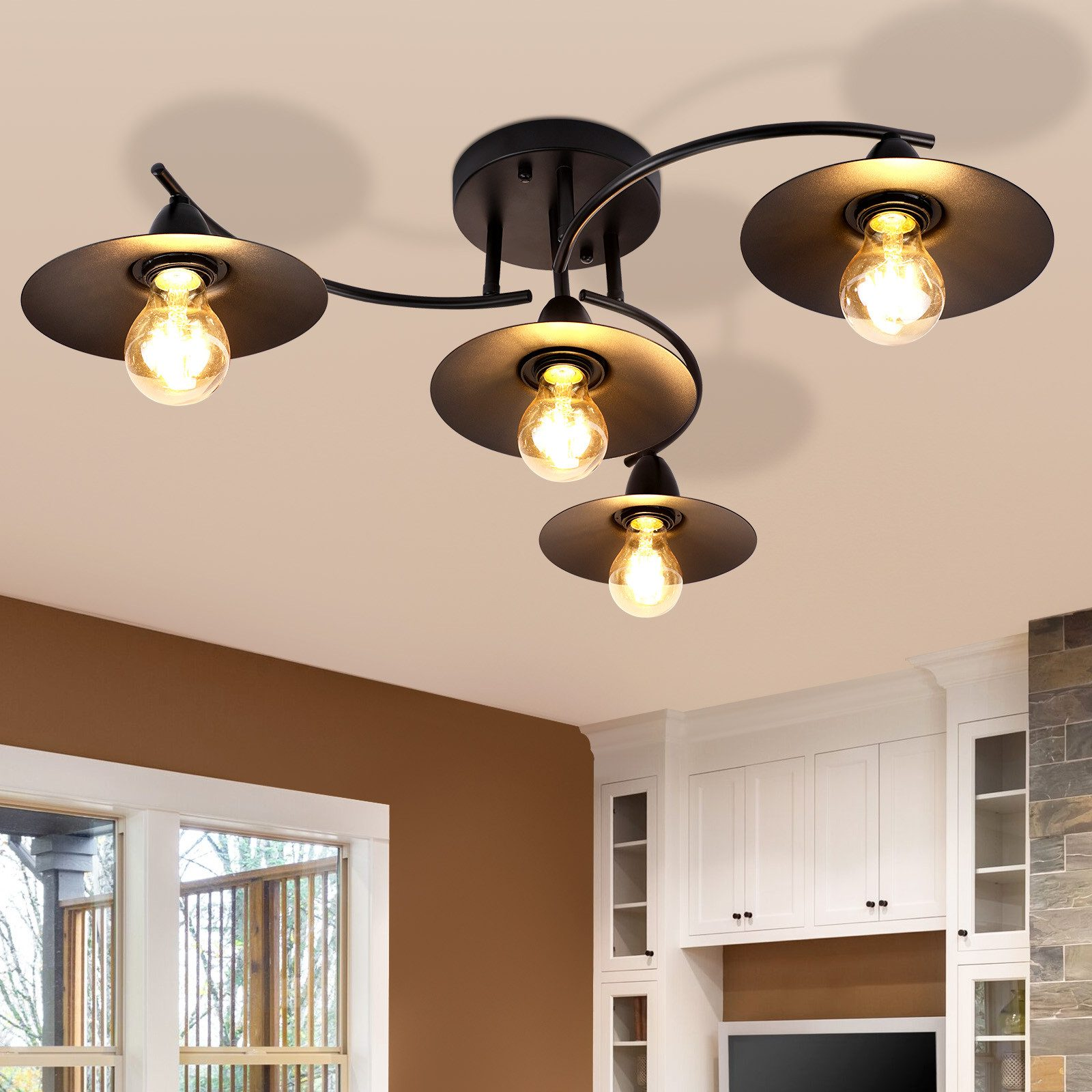 Lampada da soffitto nera con quattro lampade, ciascuna con paralume rotondo e lampadine.