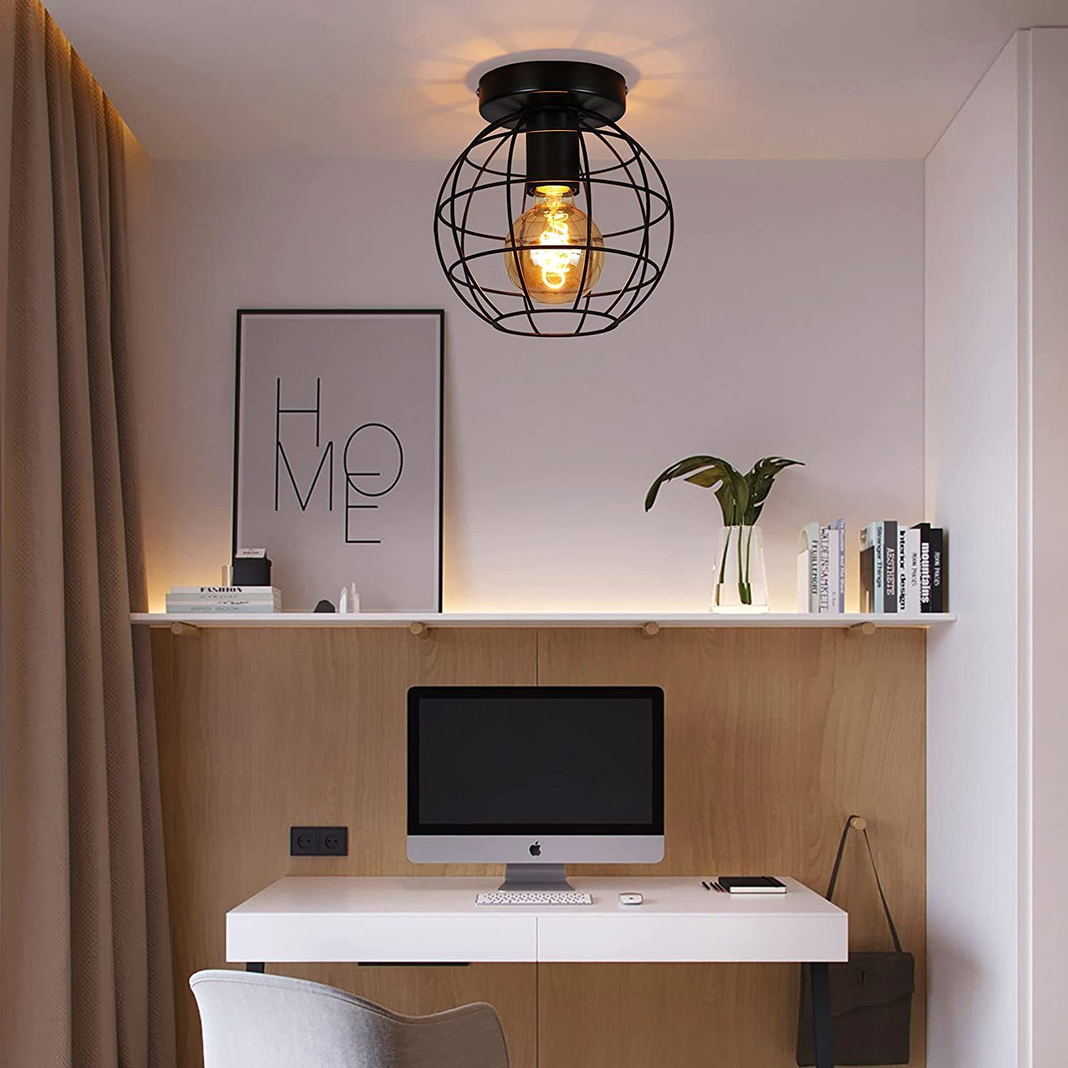 Un apparecchio di illuminazione a gabbia di filo sferico nero con una lampadina. La lampada è appesa sopra una scrivania.