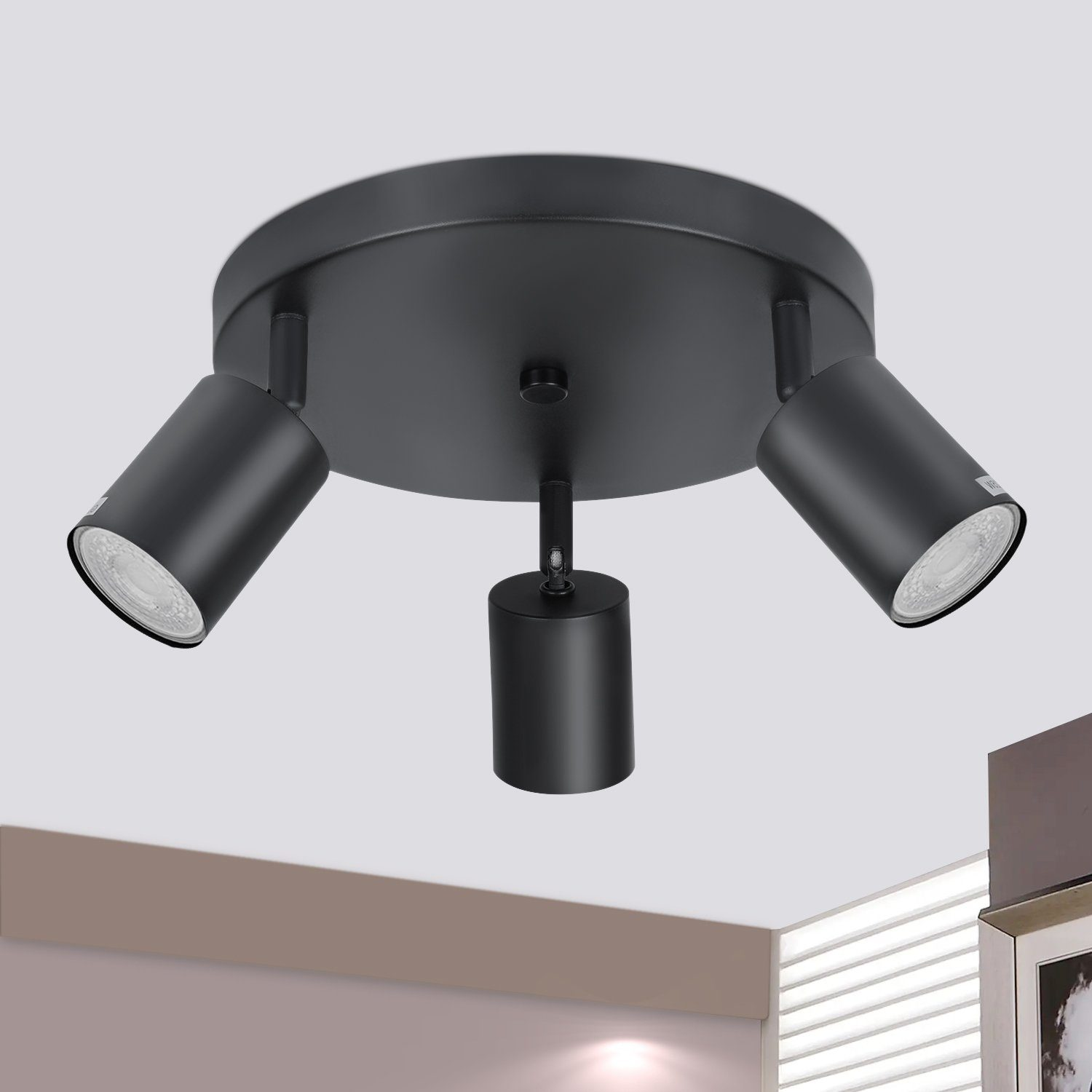 Una plafoniera nera con tre faretti orientabili. La luce è montata su una base circolare.