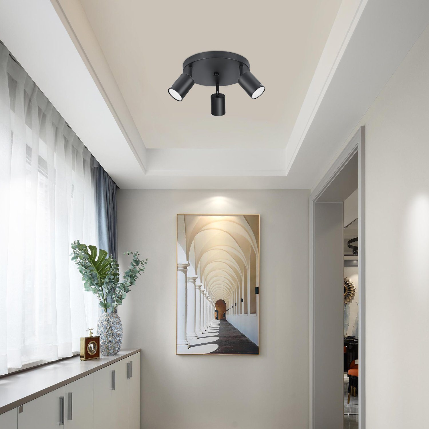 Lampada da soffitto nera con tre faretti in un corridoio.