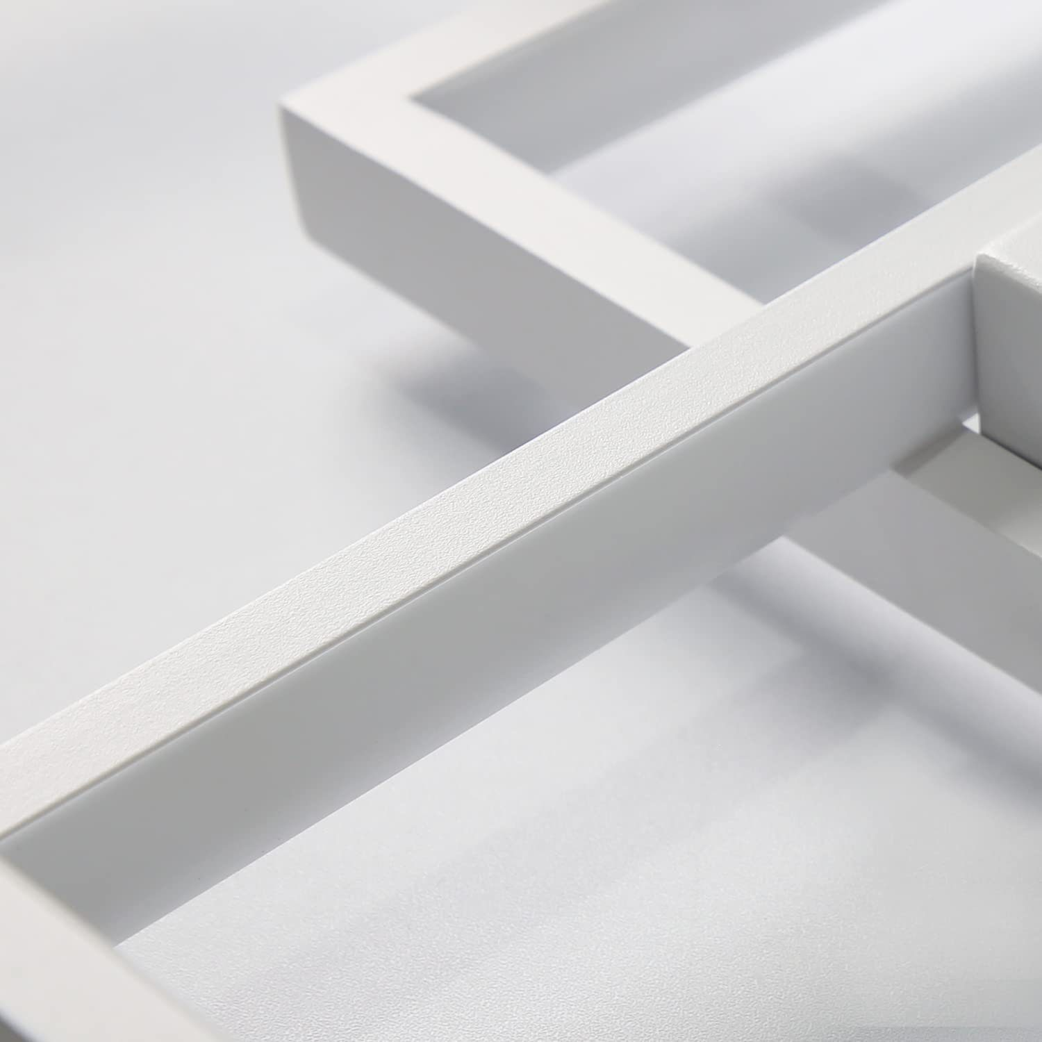 Primo piano di un apparecchio di illuminazione a soffitto bianco e geometrico con un design minimalista.