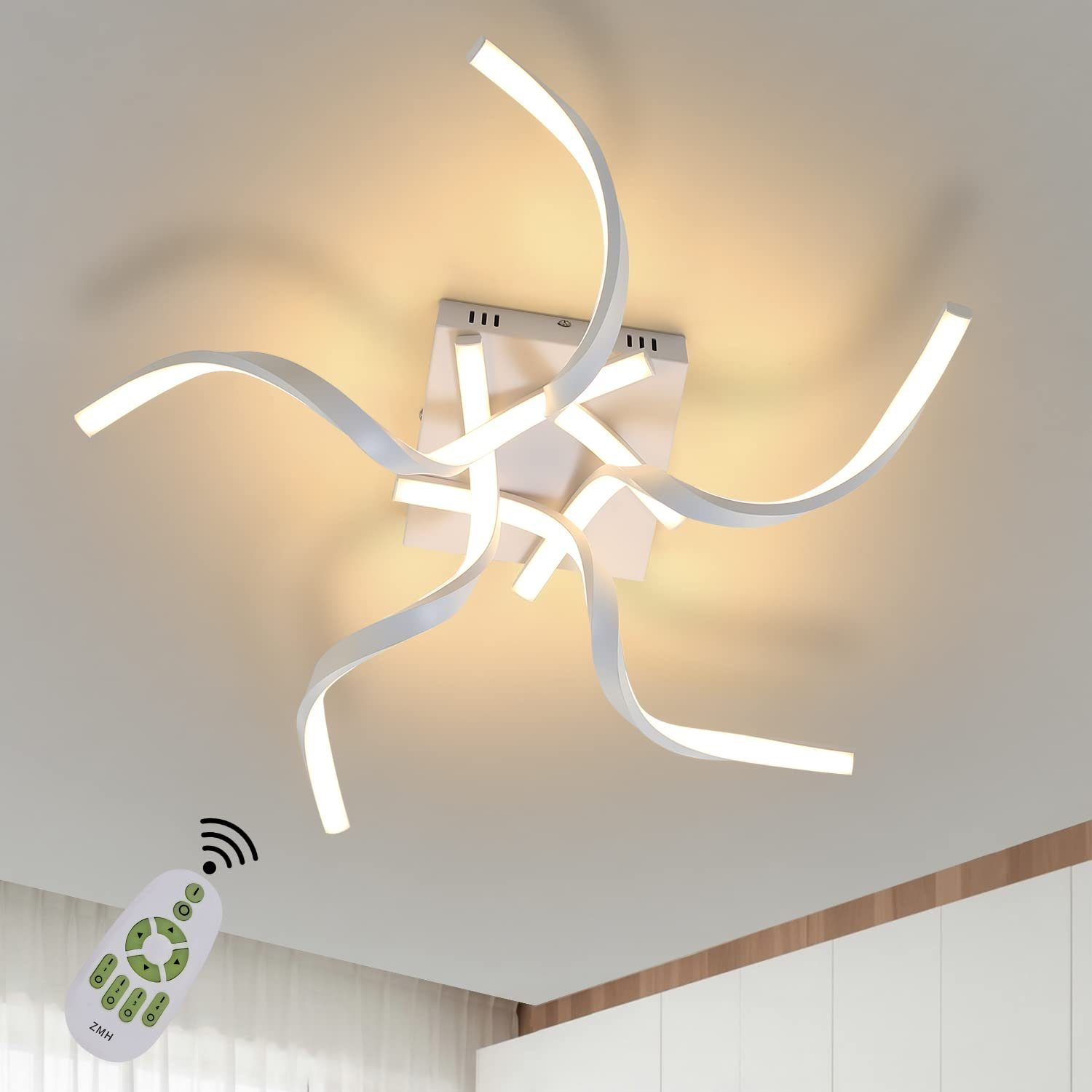 Una moderna plafoniera con bracci bianchi e curvi, con un telecomando. La luce è accesa.