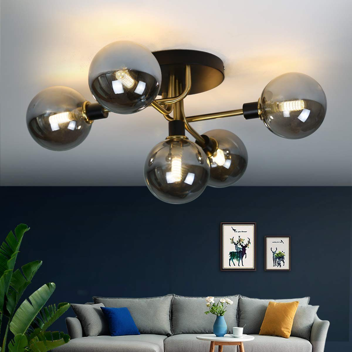 Lampa sufitowa z pięcioma kulistymi światłami. Pokój ma ciemnoniebieską ścianę i szarą sofę.