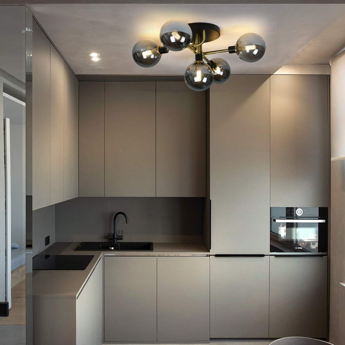Nowoczesna kuchnia z szarymi szafkami, czarnym zlewem i lampą sufitową z szklanymi kulami.