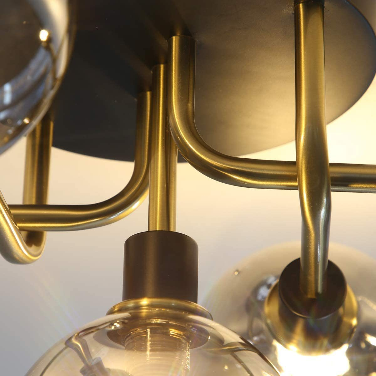 Zbliżenie lampy sufitowej z mosiężnymi wspornikami i czarną podstawą.