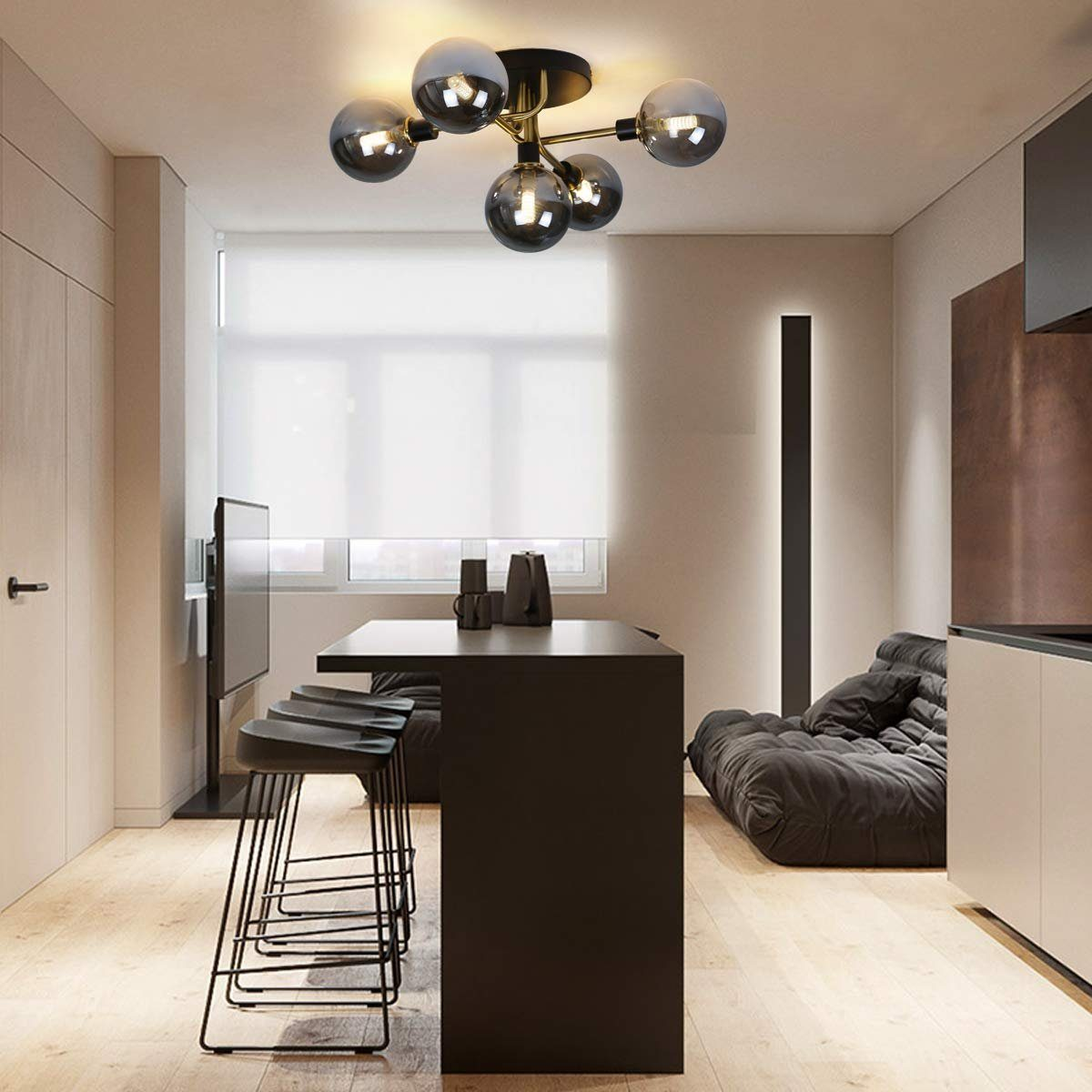 Salon z lampą wiszącą z sześcioma kulistymi światłami i hokerami.