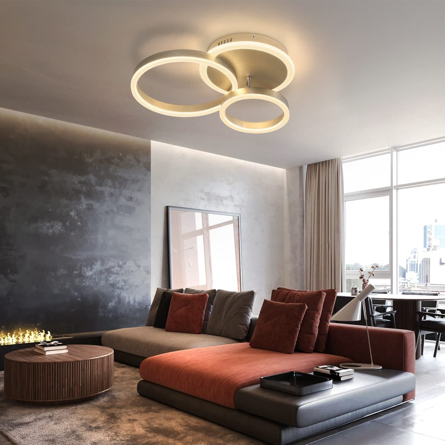 Lampa sufitowa z trzema połączonymi białymi pierścieniami w salonie z sofą, sztuką i dużym oknem.